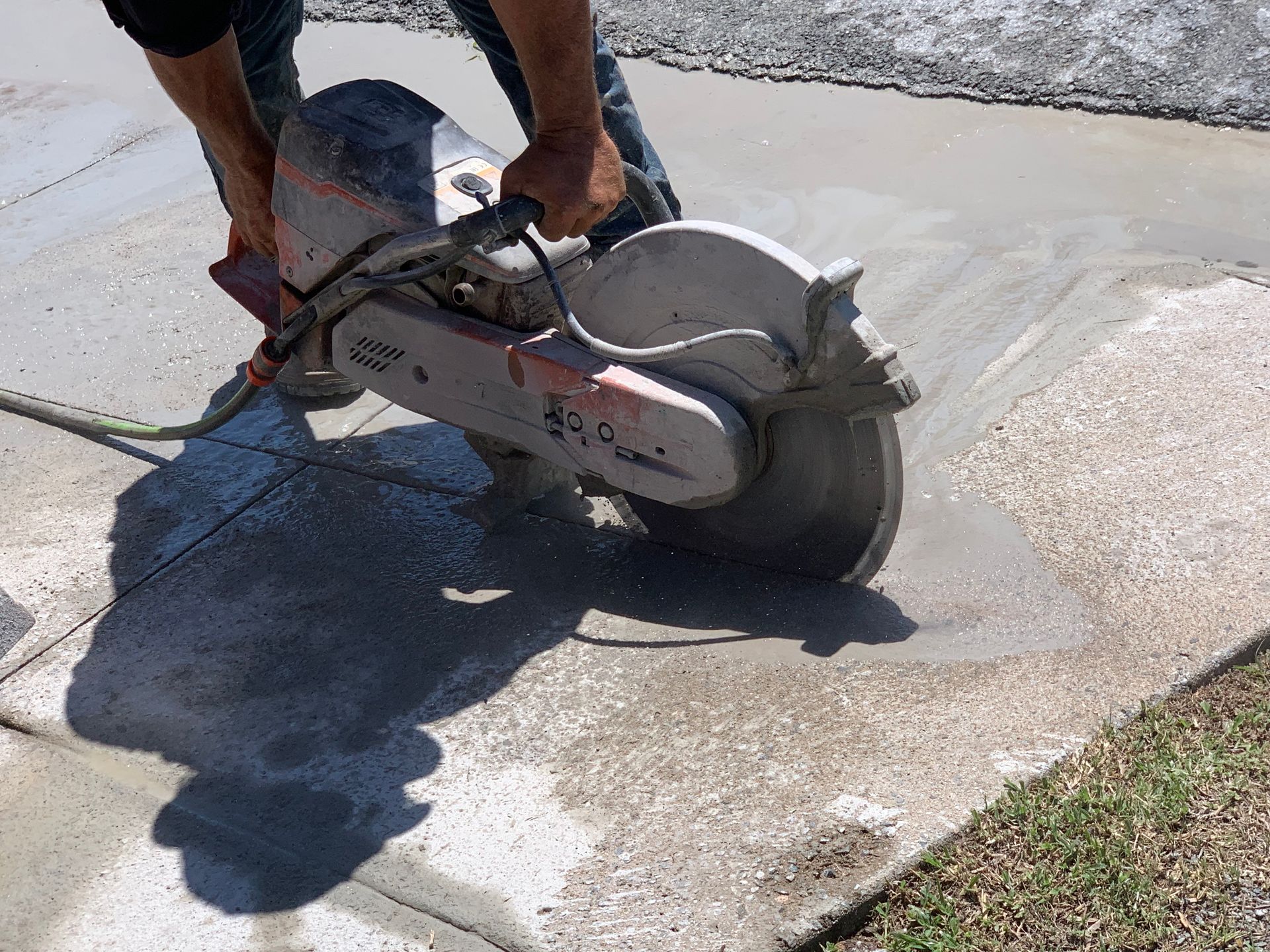Worker using a concrete saw to cut wet pavement outdoors — Ablecut Concrete Cutting & Coring In East Mackay, QLD