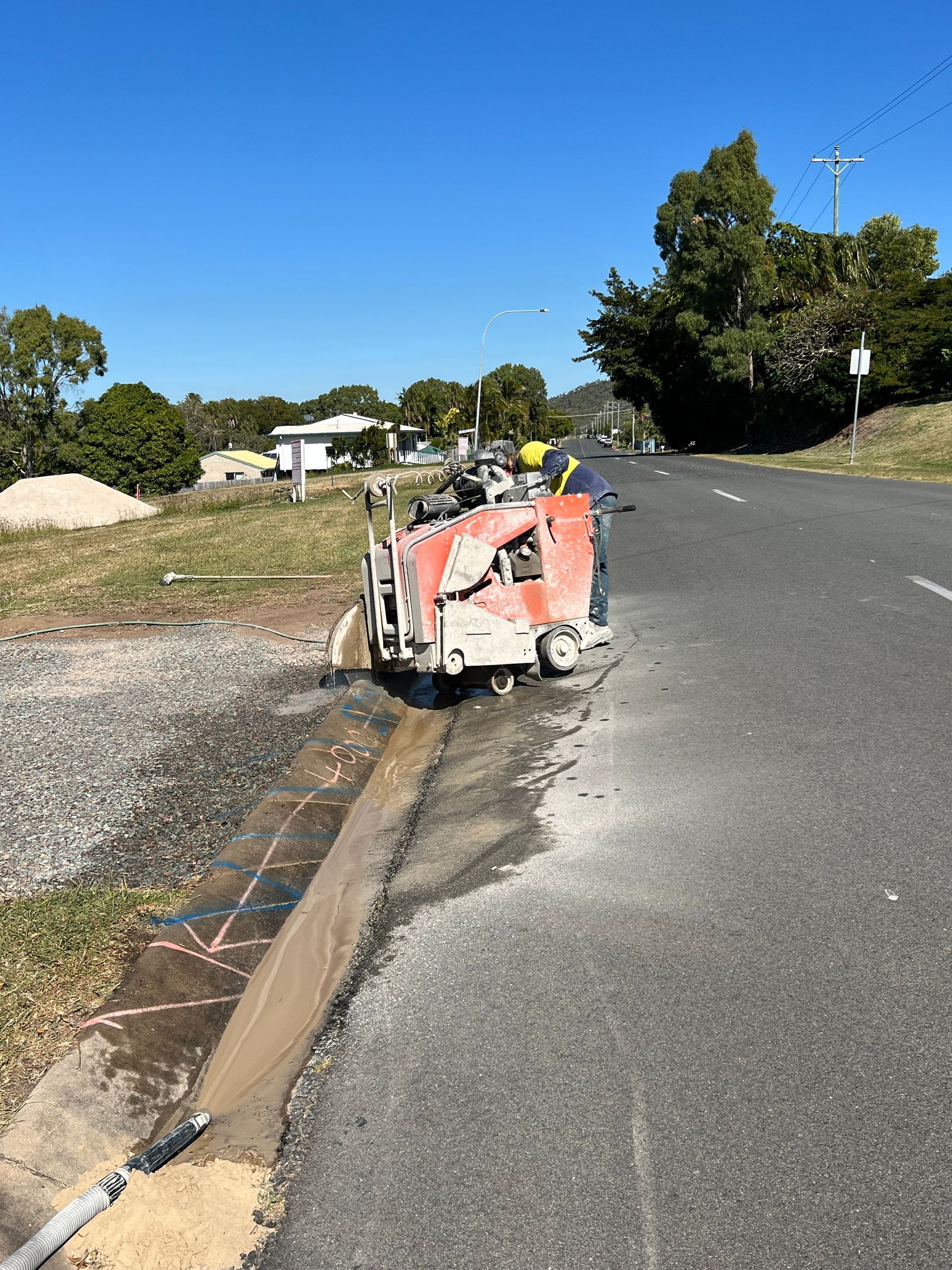 Red utility cart tipped on its side beside a road curb under a clear blue sky. — Ablecut Concrete Cutting & Coring In East Mackay, QLD