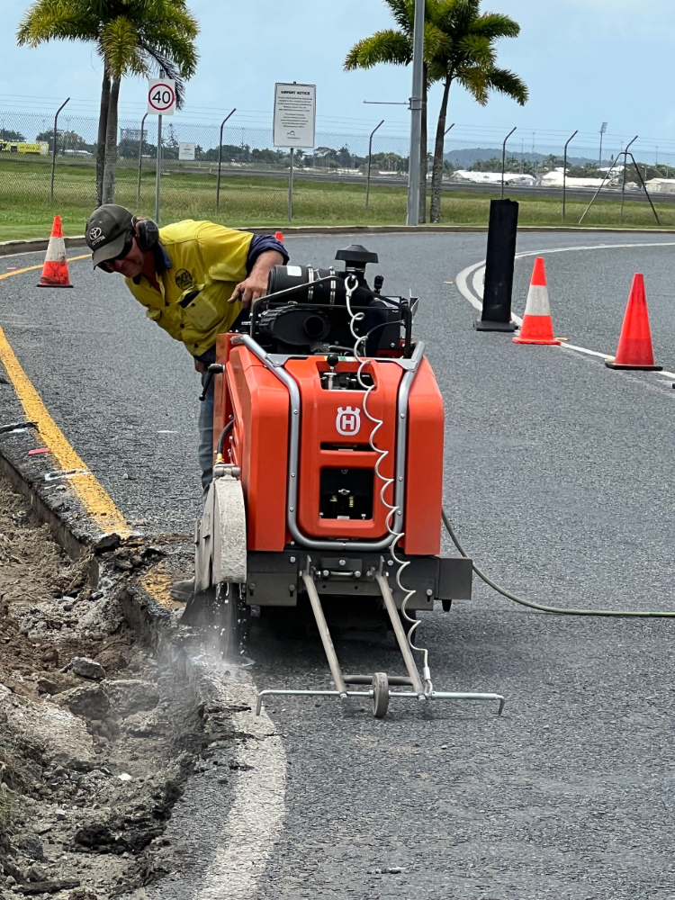 Man Operating a Concrete Saw to Cut a Roadway — Ablecut Concrete Cutting & Coring In East Mackay, QLD
