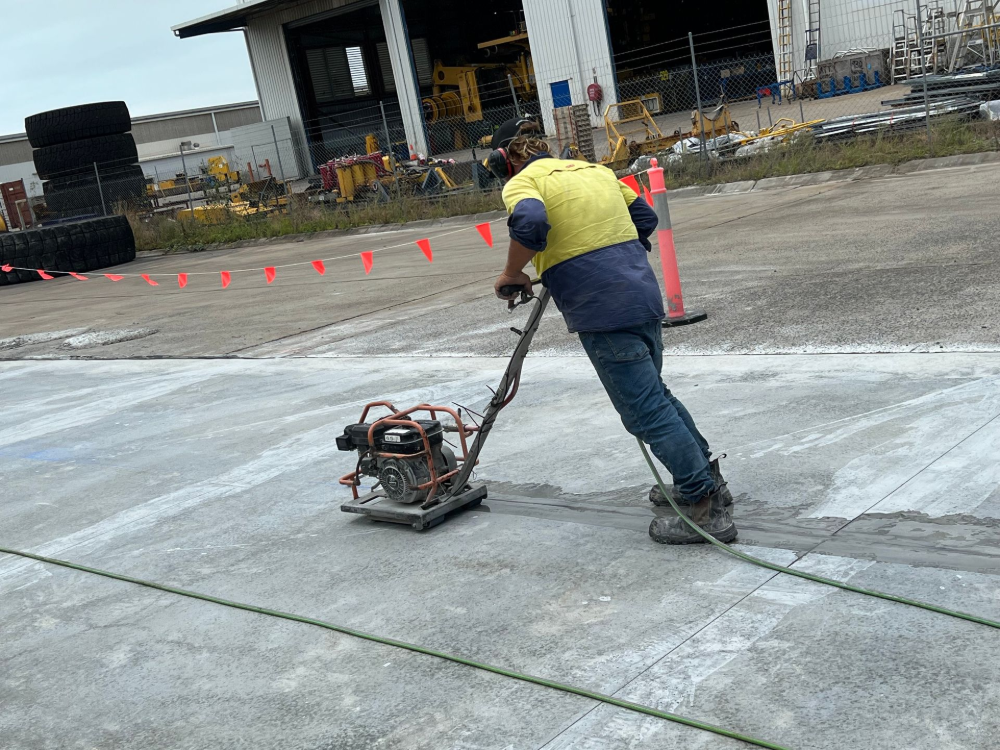 Person Using a Plate Compactor on Concrete in an Industrial Area — Ablecut Concrete Cutting & Coring In East Mackay, QLD