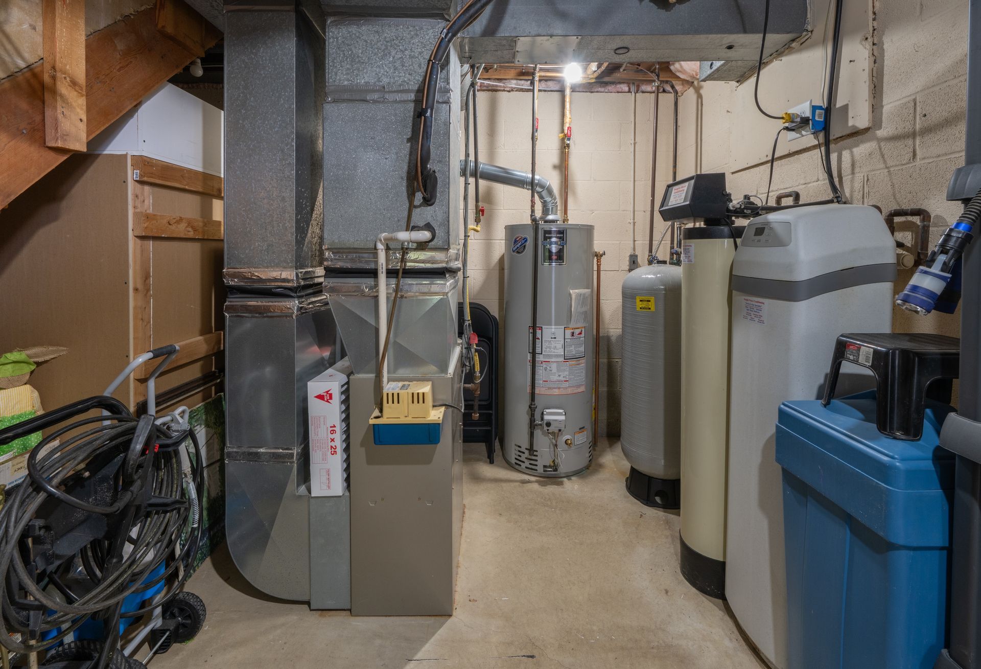 Oil furnace, silver with black components. Ductwork and fuel line visible. Red safety switch is on the left.
