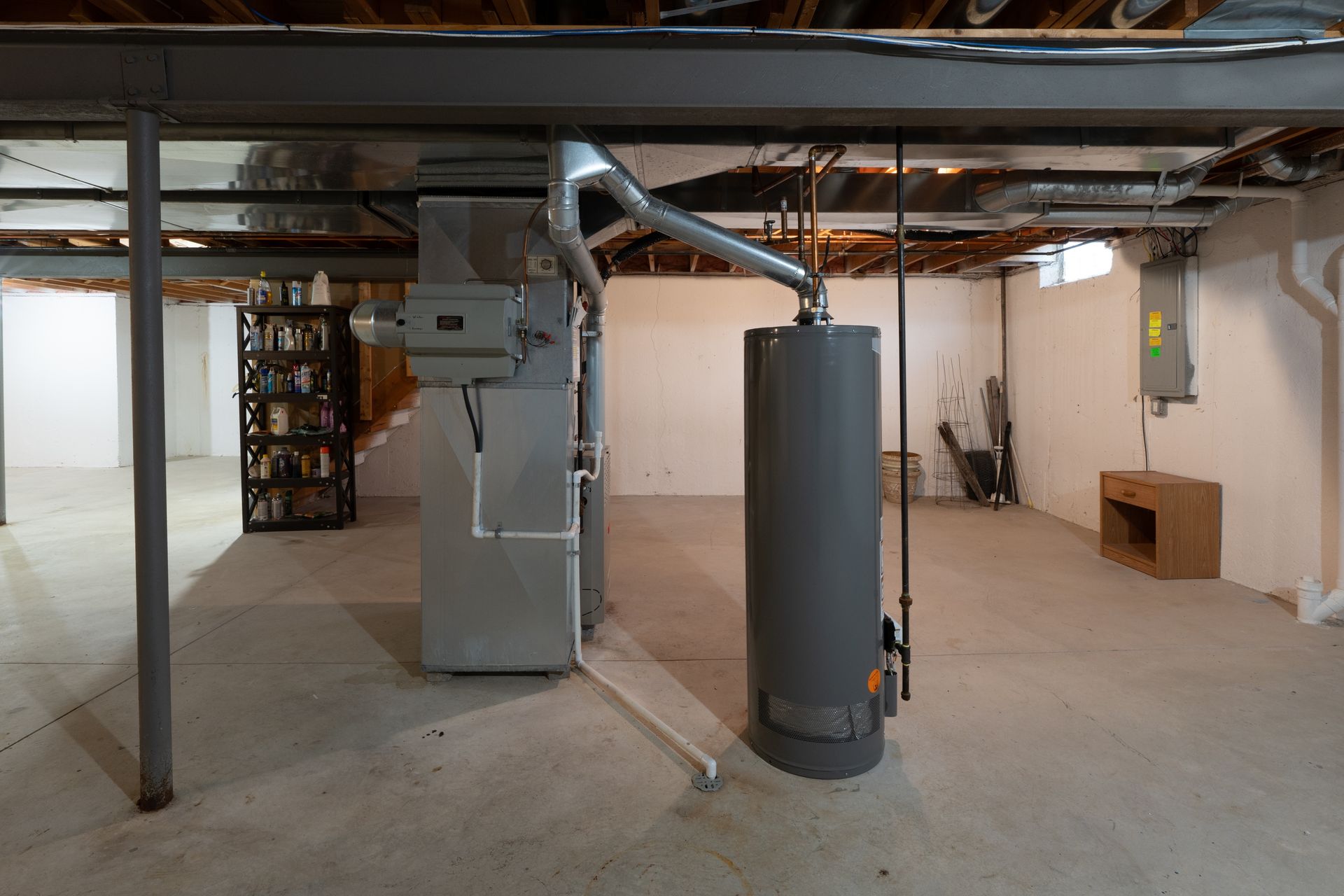 Oil furnace, silver with black components. Ductwork and fuel line visible. Red safety switch is on the left.