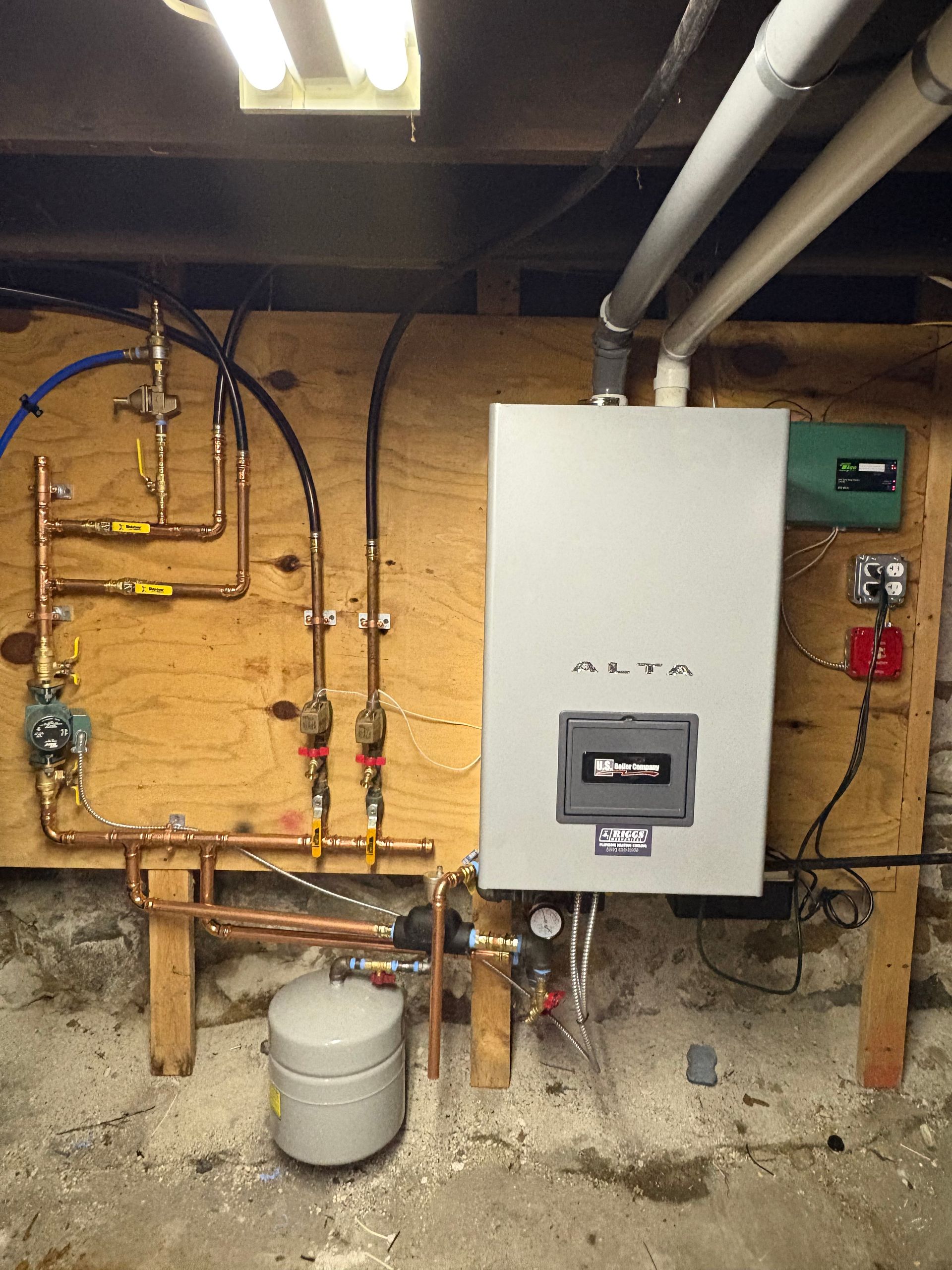 Copper pipes and water heater on a wooden wall. Various gauges, valves, and electrical components present.