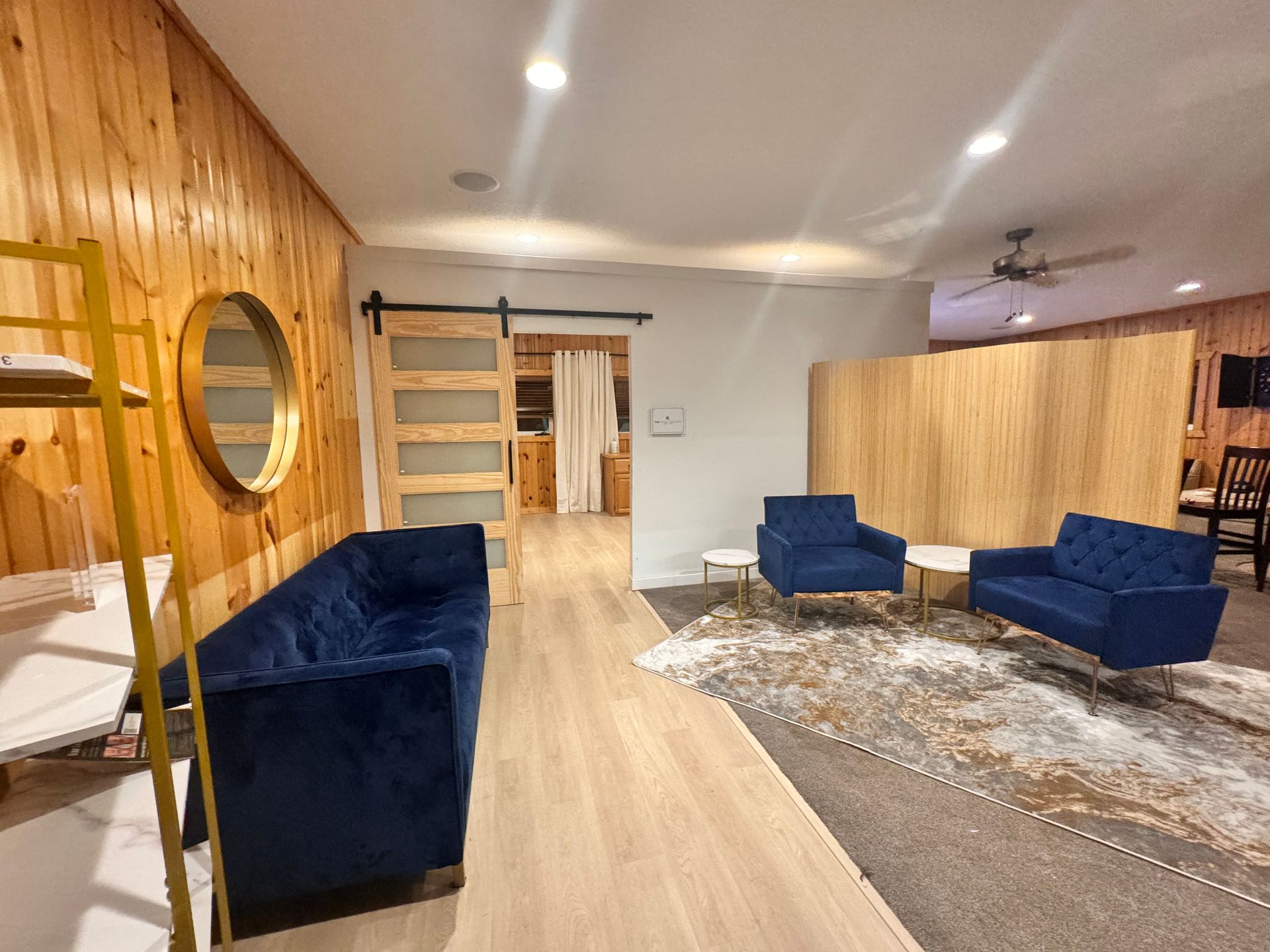 A living room with a couch , chairs , and a mirror.