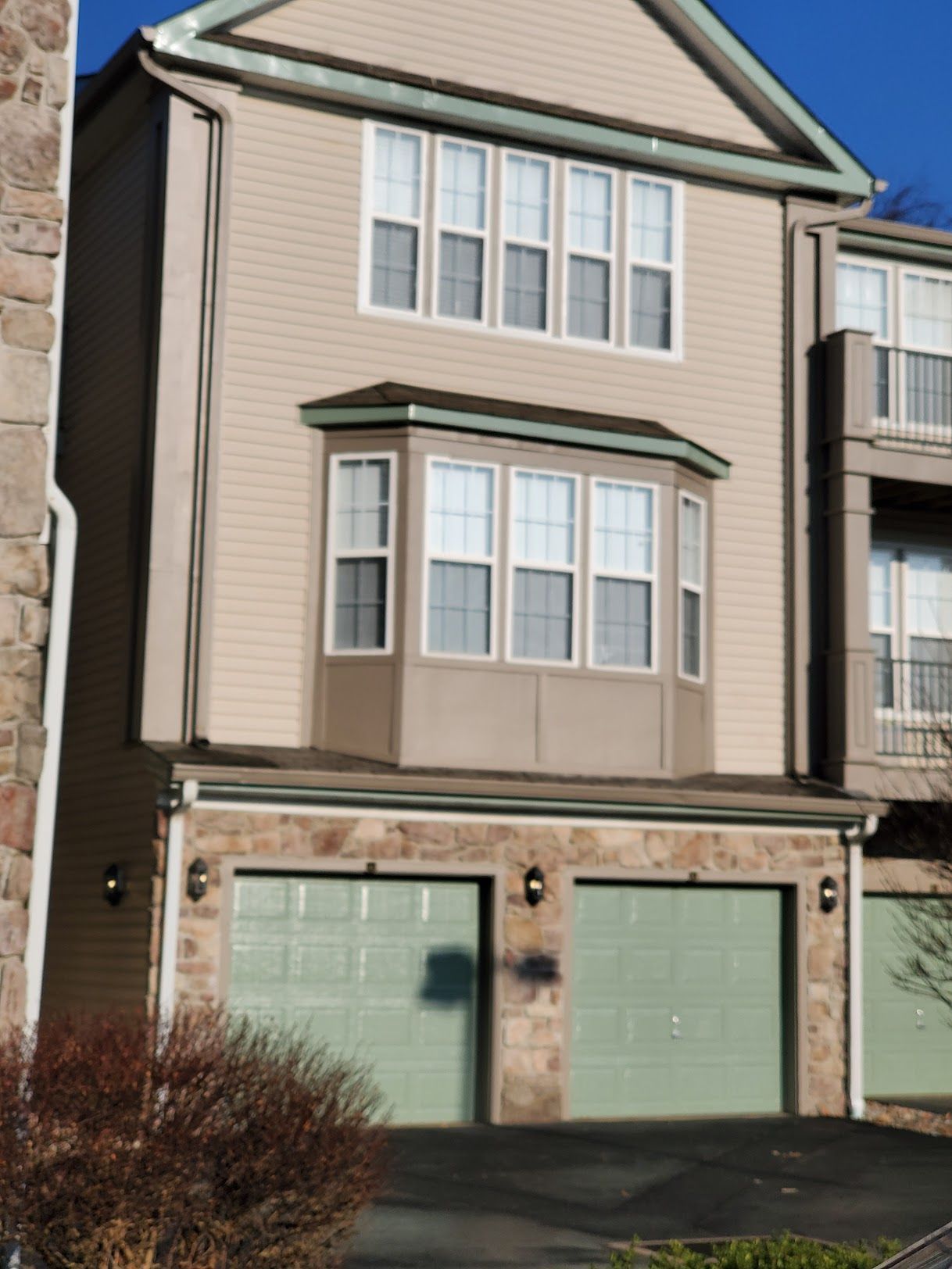 A house with a lot of windows and green garage doors