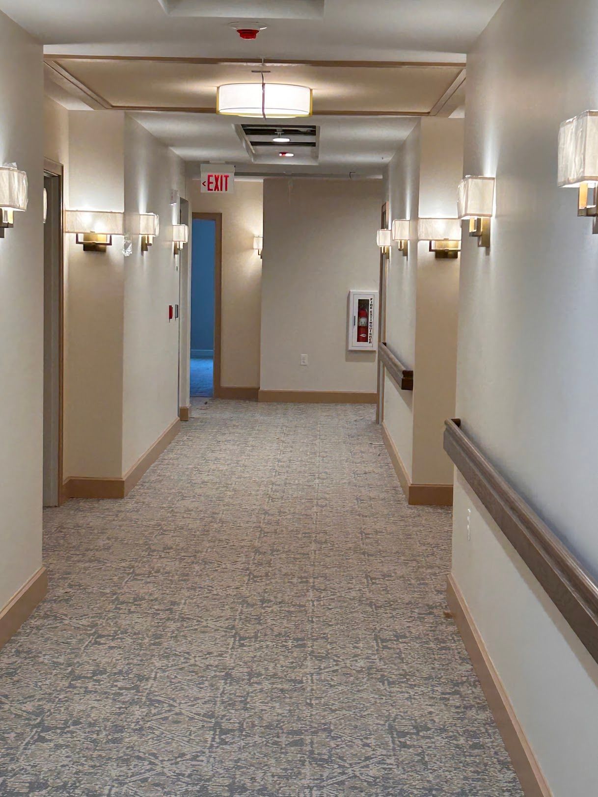 A long hallway with a fire extinguisher on the wall.