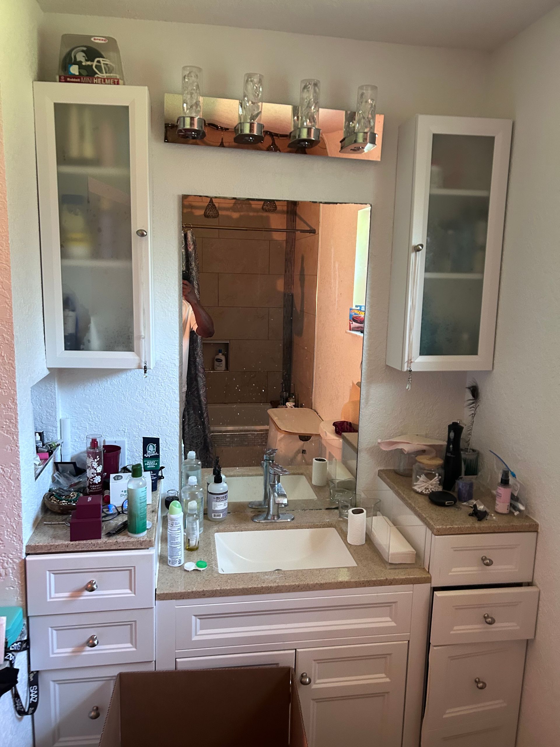 Bathroom vanity with mirror, sink, cabinets, and overhead lighting.