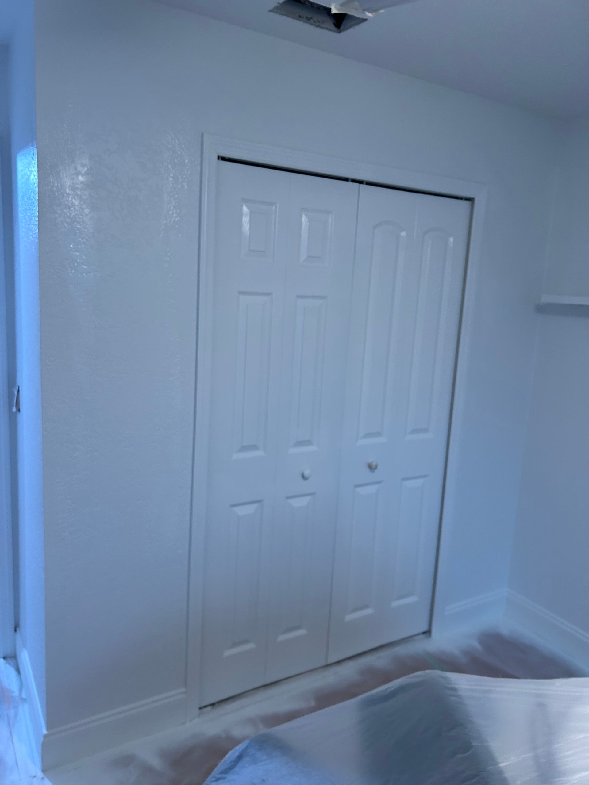 White bi-fold closet doors in a freshly painted room with white walls and trim.