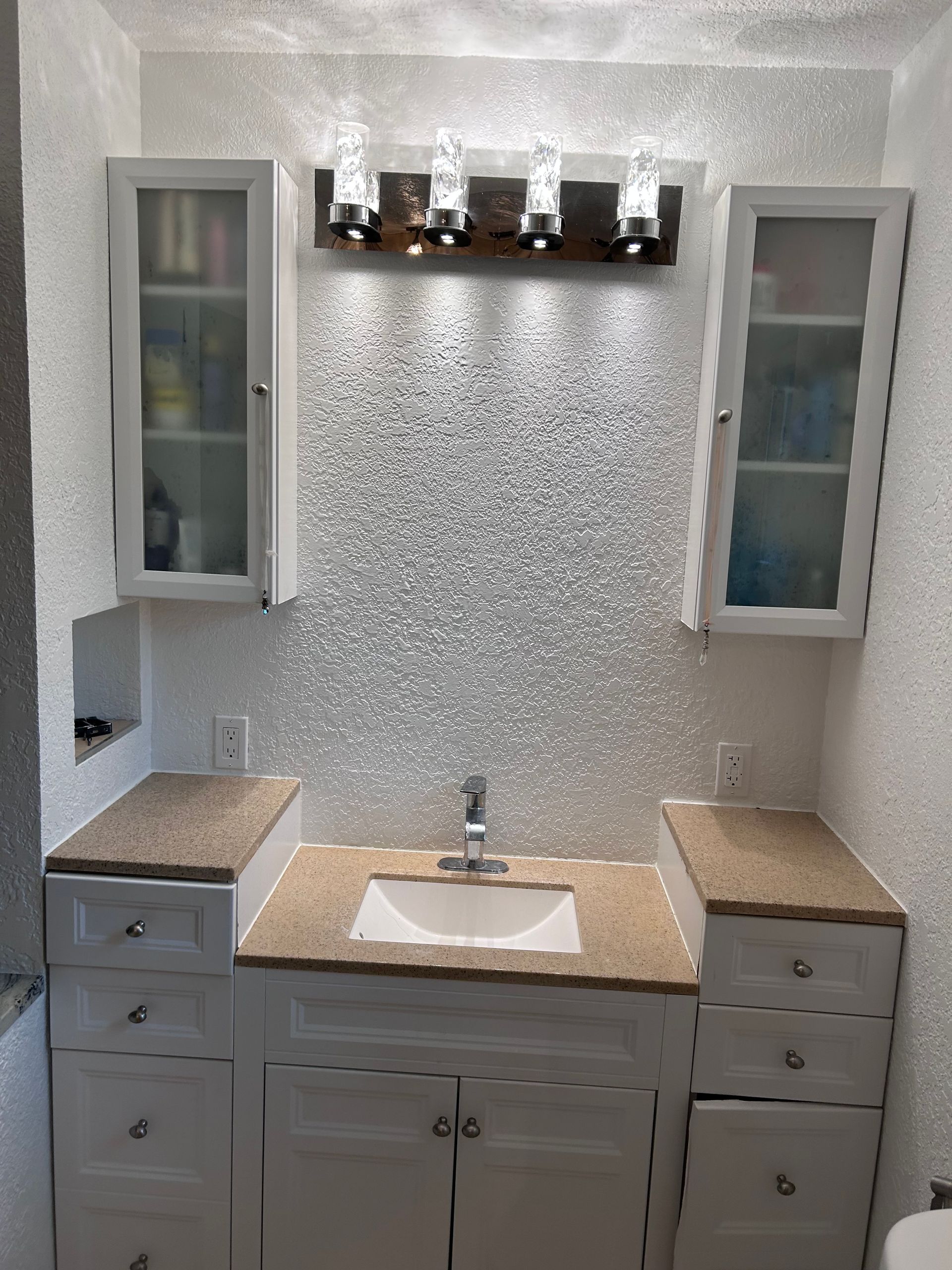 Bathroom with white cabinets, glass tile backsplash, and overhead lighting.