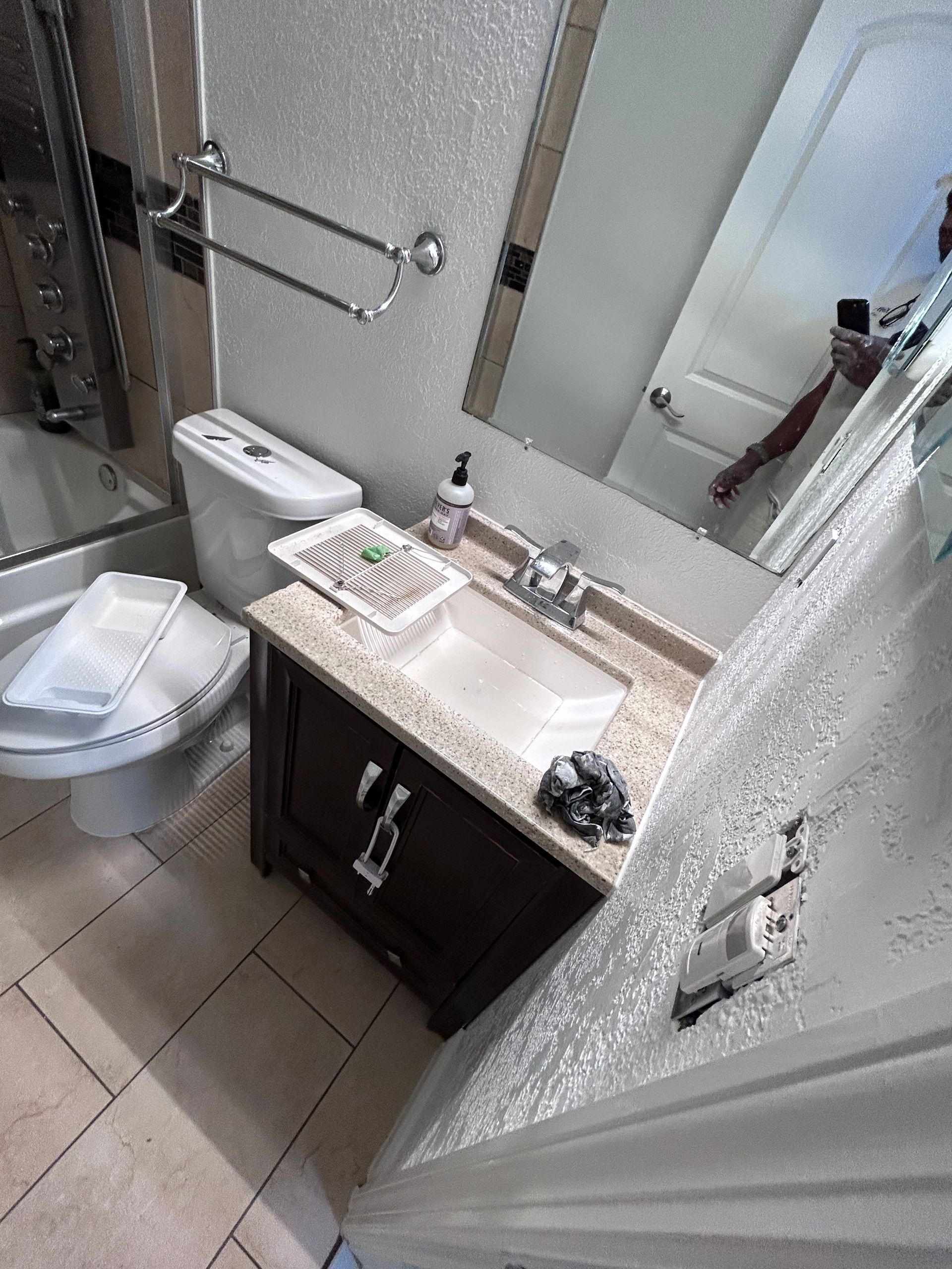 Bathroom with toilet, vanity with sink, and mirror. White and beige tones.