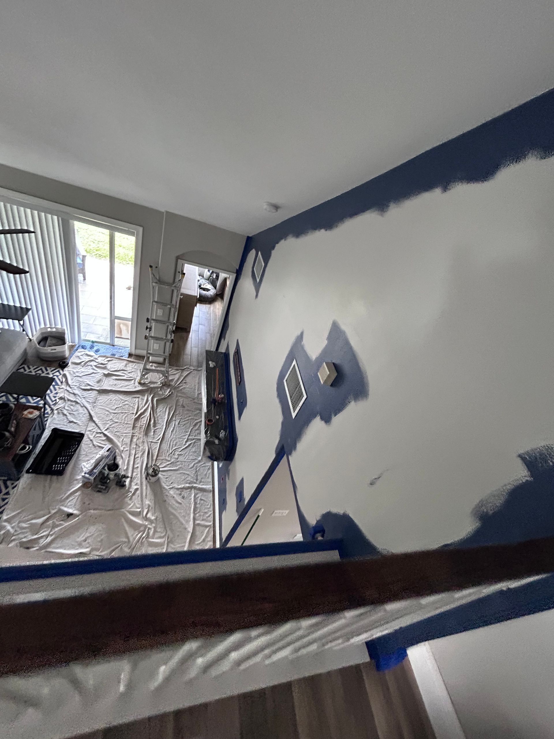 A room being painted blue. Painter's tape and supplies on the floor. White walls with blue trim.