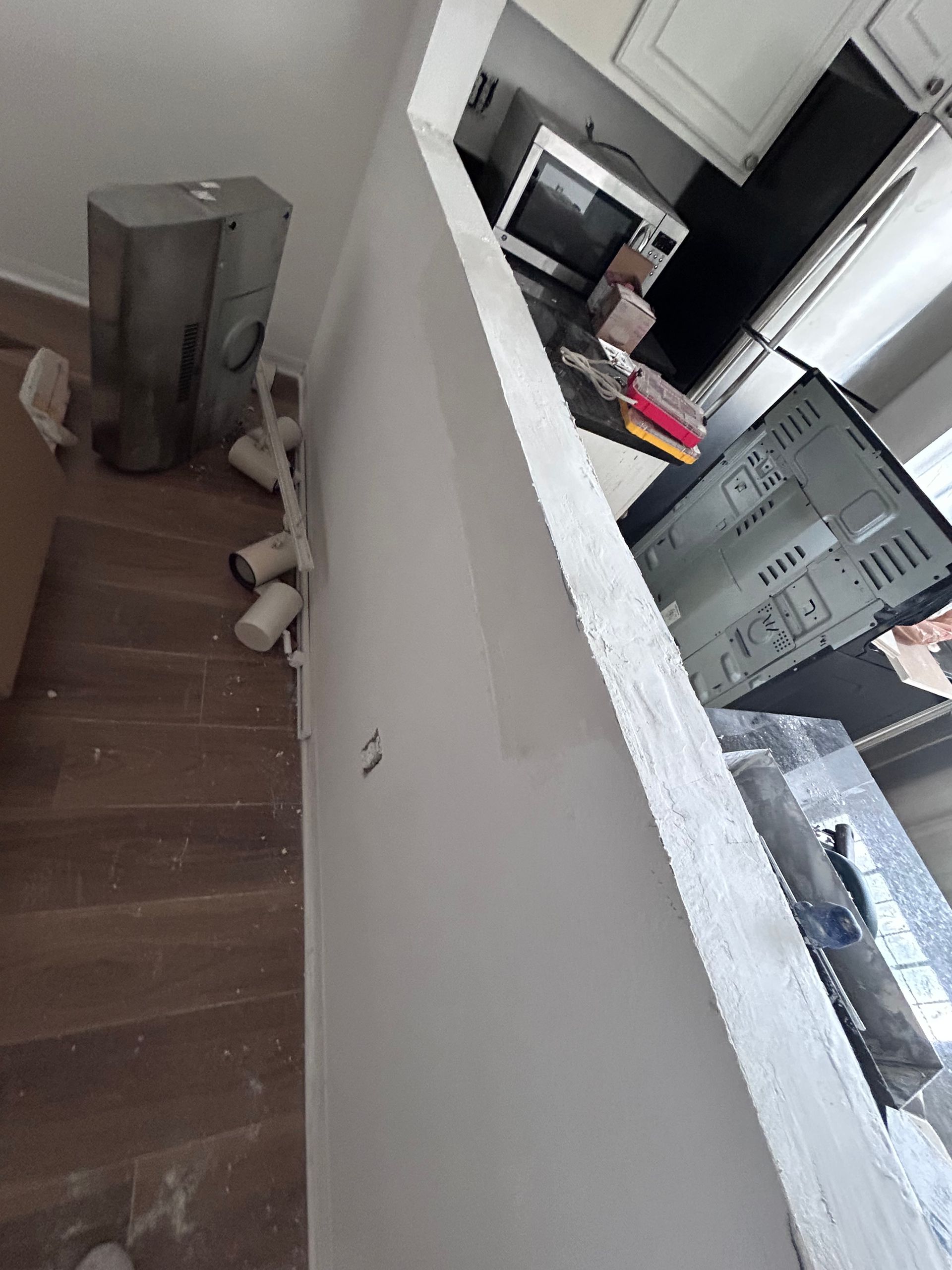 Interior view of a kitchen under renovation, with a partially constructed wall and appliances.
