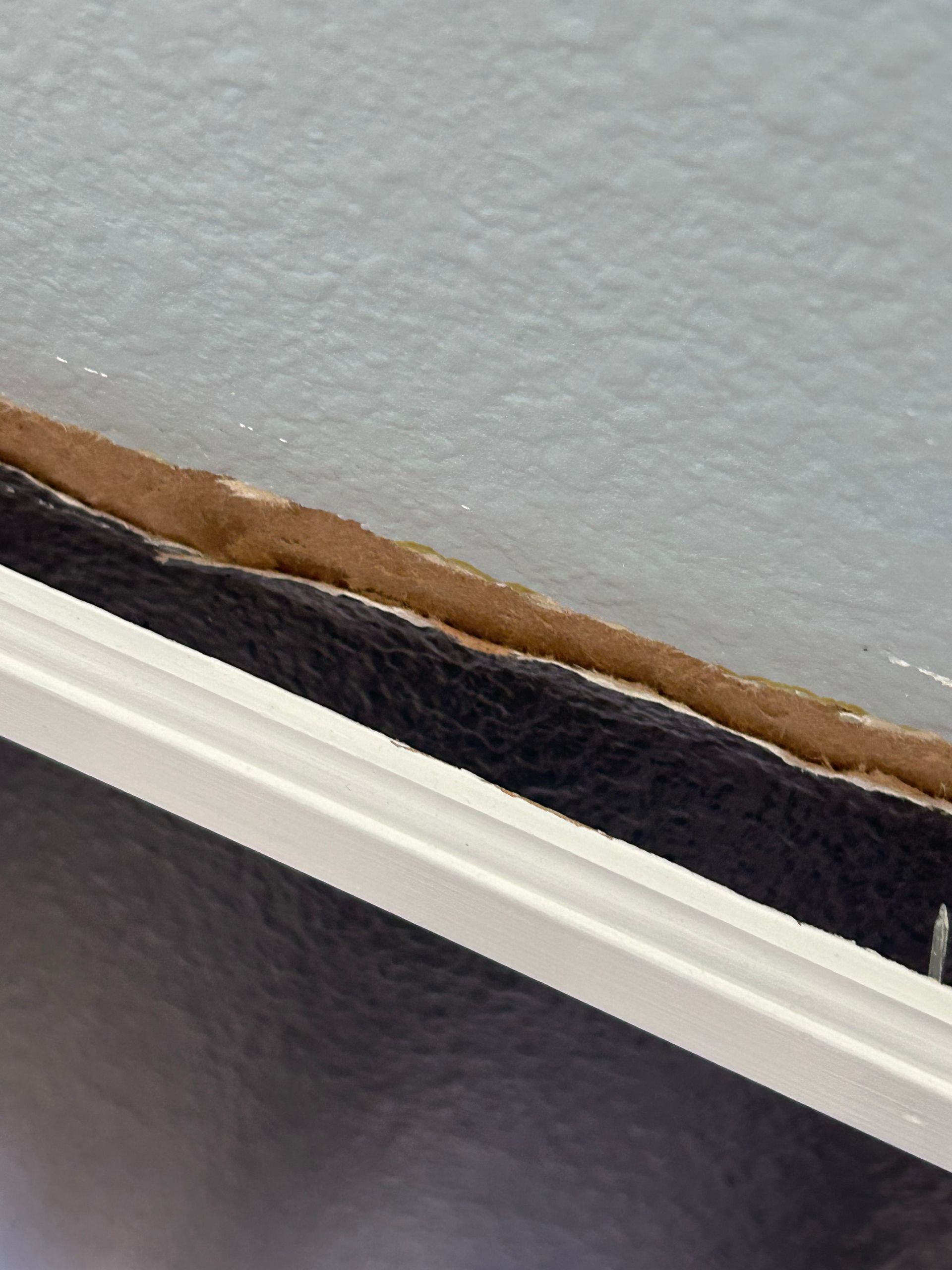 Close-up of a black leather surface with a white trim against a light-colored wall.