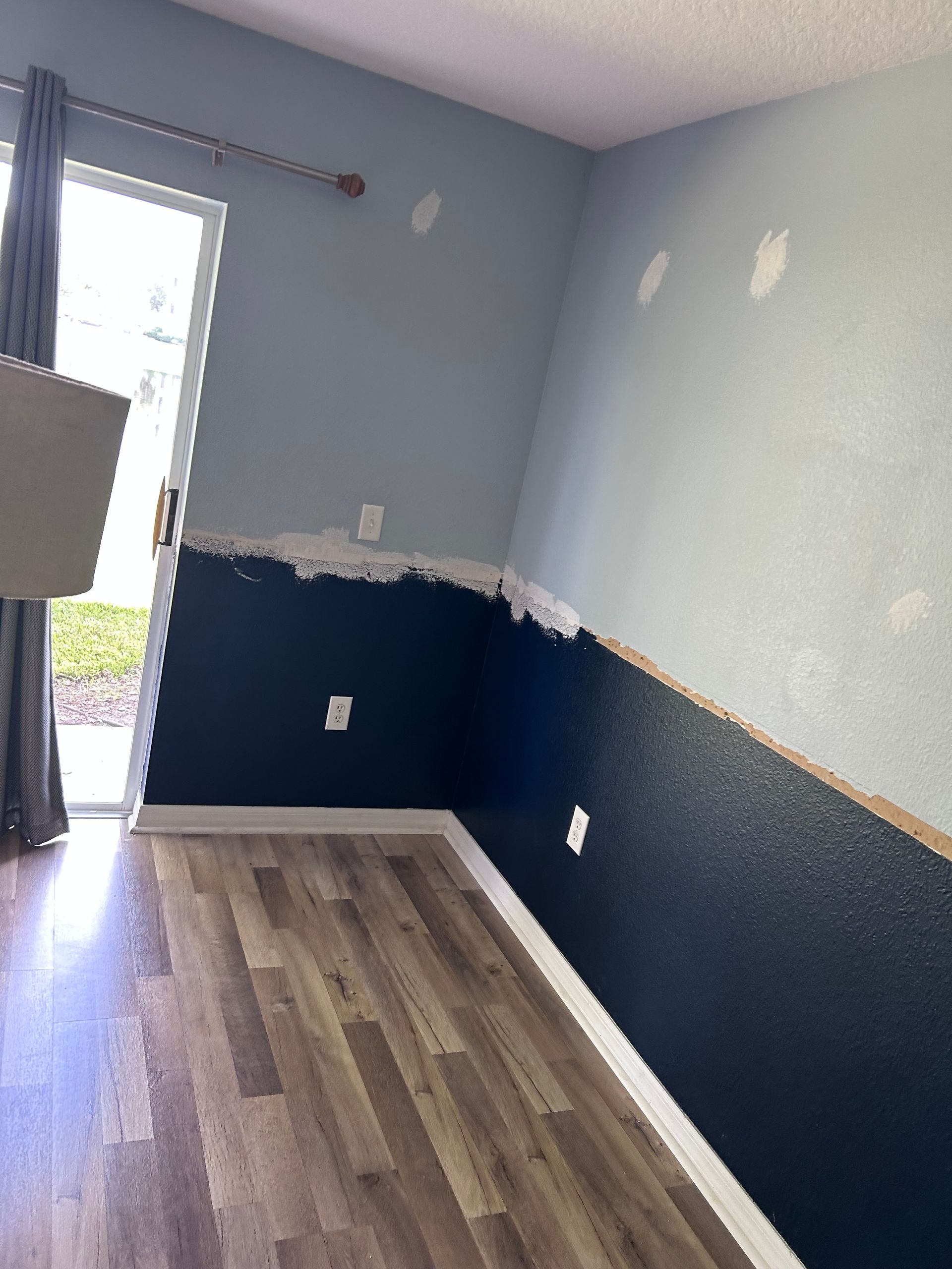 Room with dark blue and light blue painted walls, partially finished, and wood-look flooring.