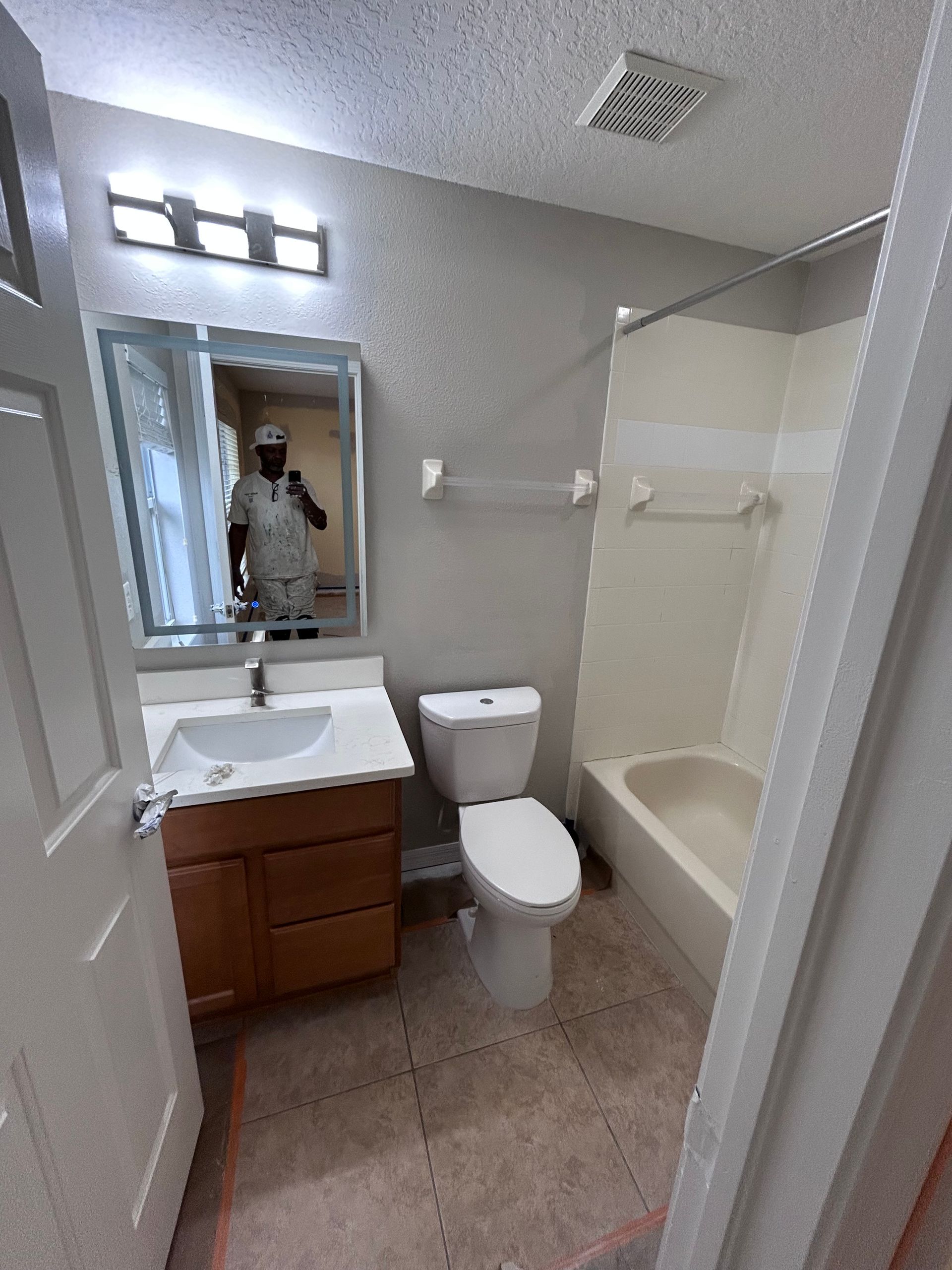 Bathroom interior with vanity, toilet, bathtub, and neutral-colored walls and floor.