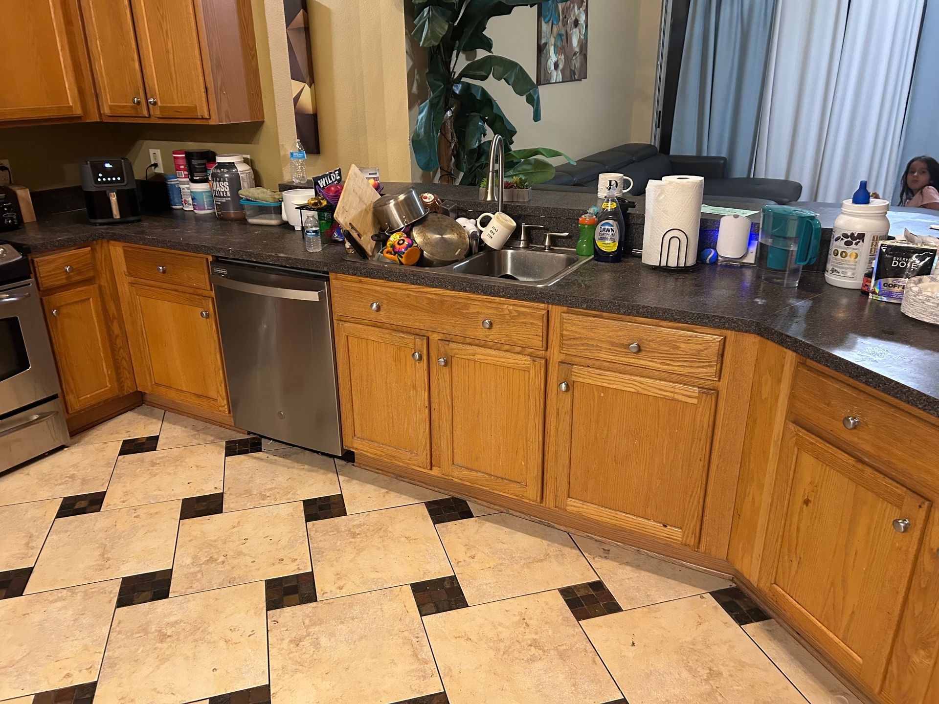 Kitchen with wood cabinets, stainless steel appliances, and a cluttered countertop.