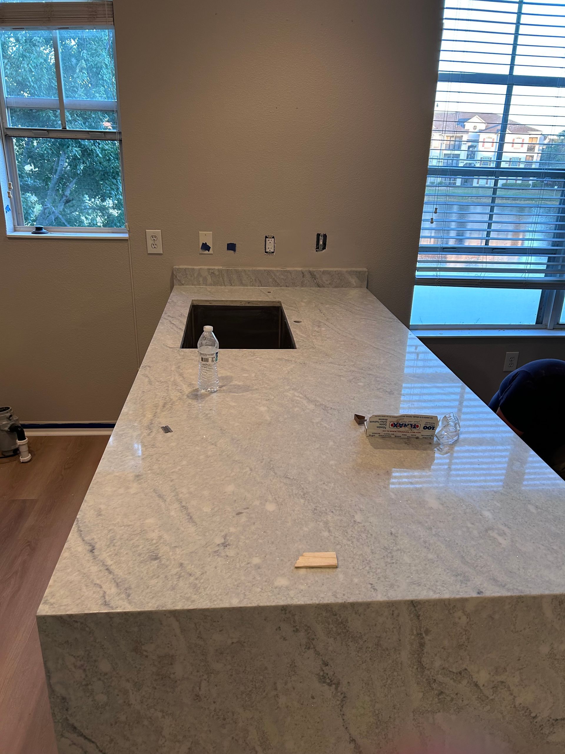 Light gray granite countertop with built-in cooktop, near windows and electrical outlets.