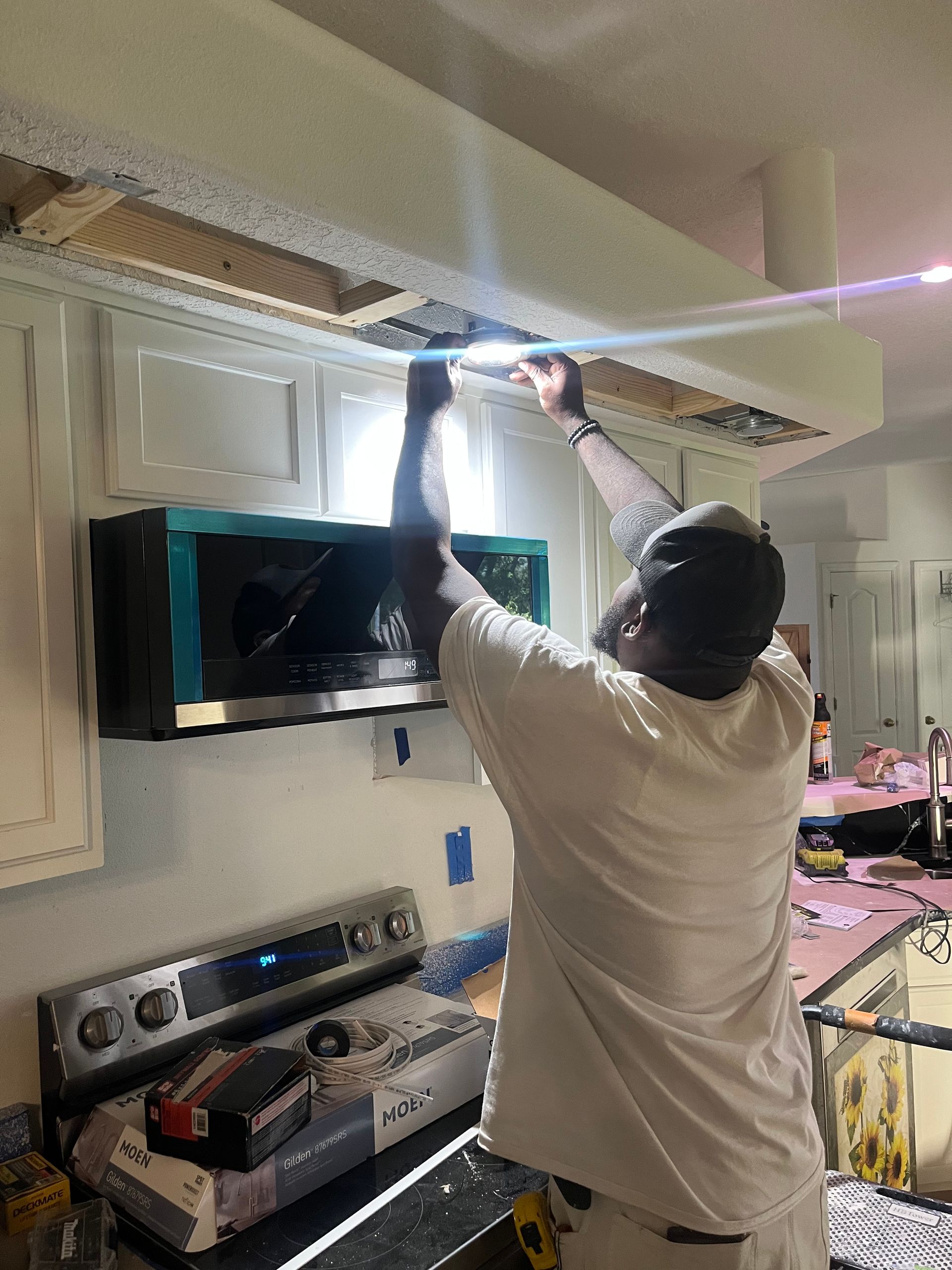 A man is working on a microwave in a kitchen.