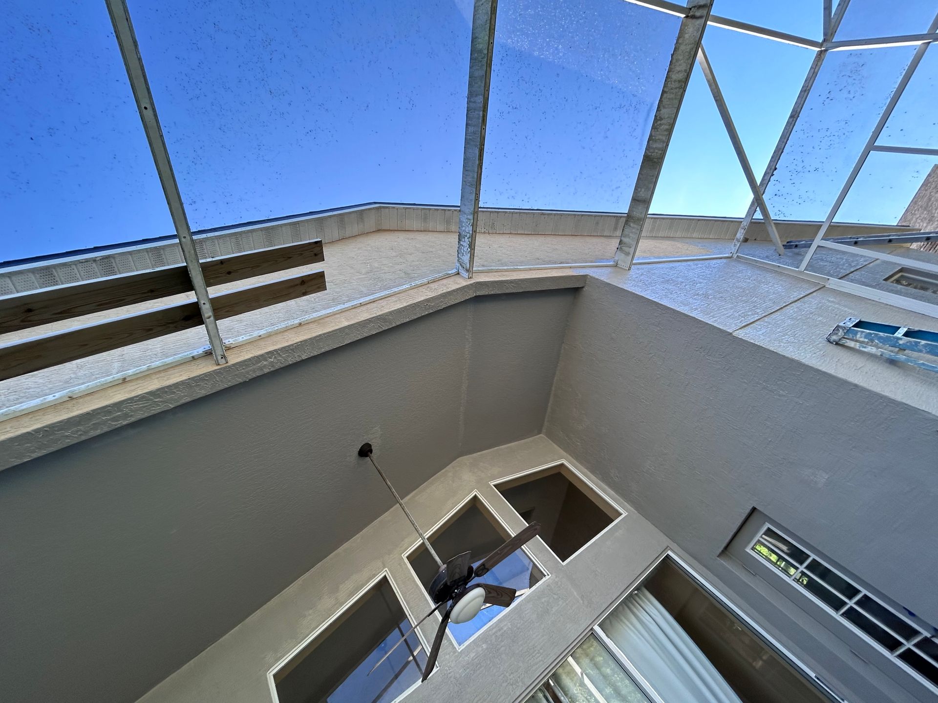 Interior view of a building with a glass roof, gray walls, and several rectangular windows.