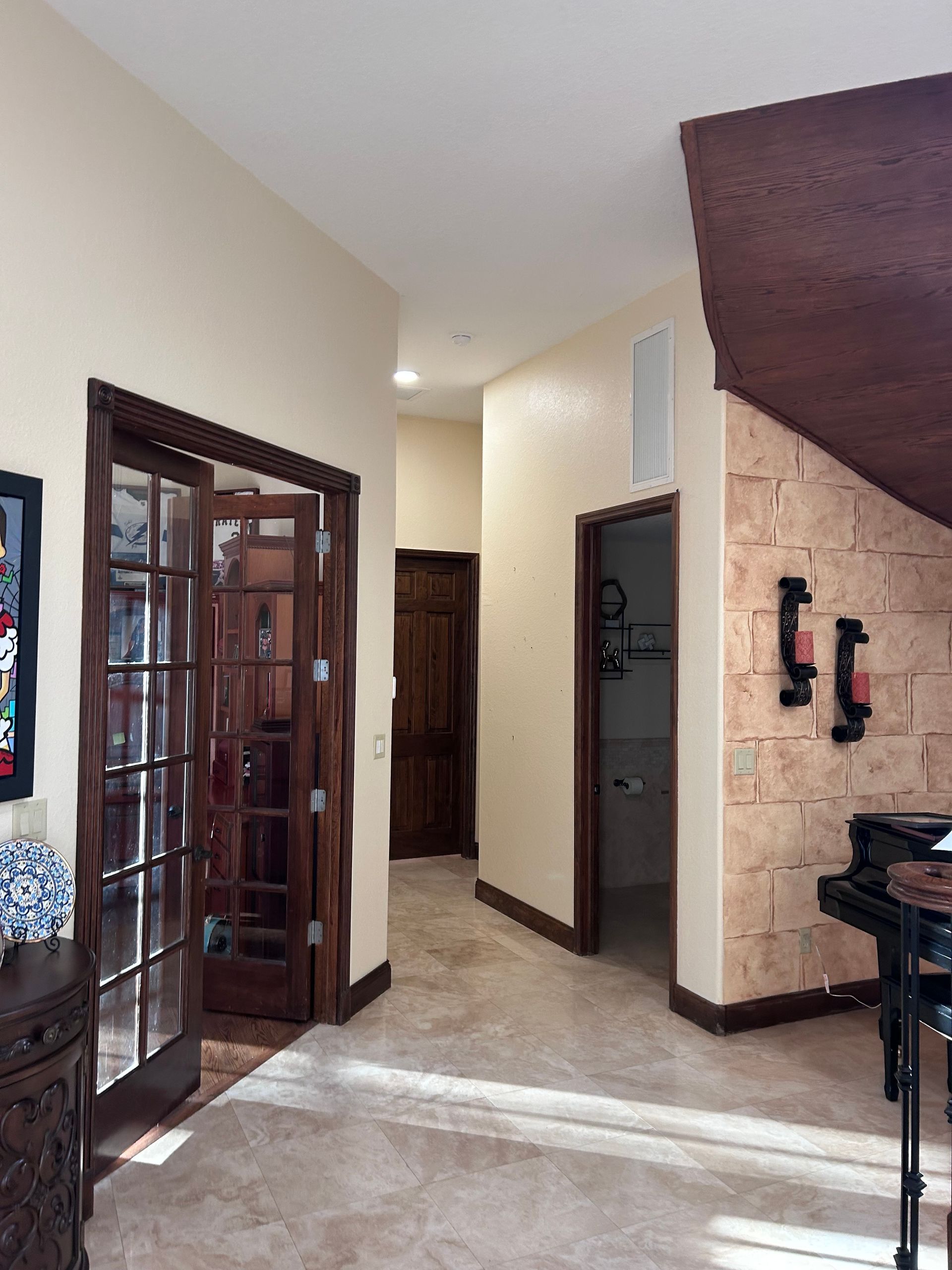 Hallway with French doors, stone wall, and dark wood trim.