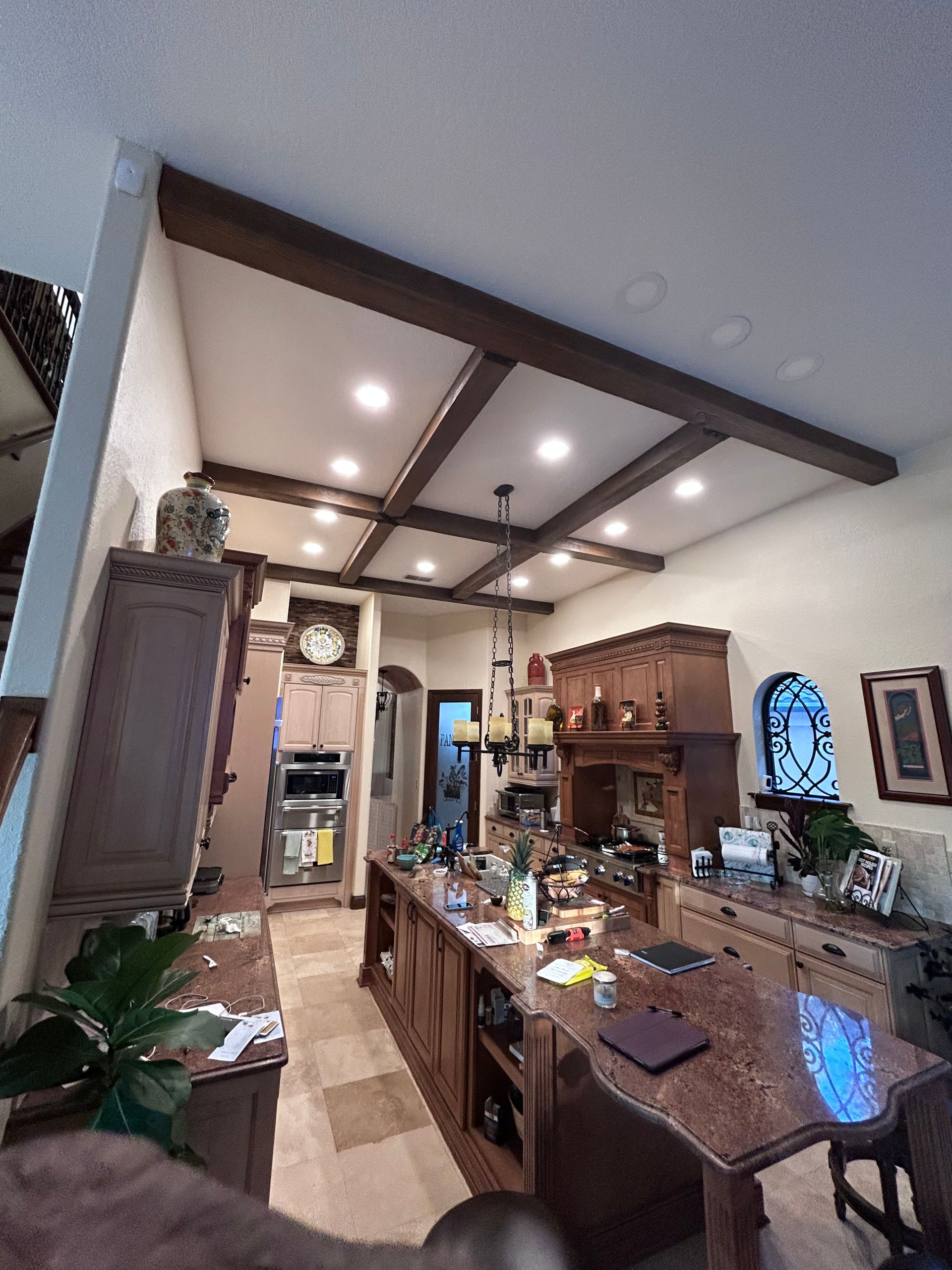 Kitchen with dark wood beams, cabinetry, and a large island with a granite countertop.