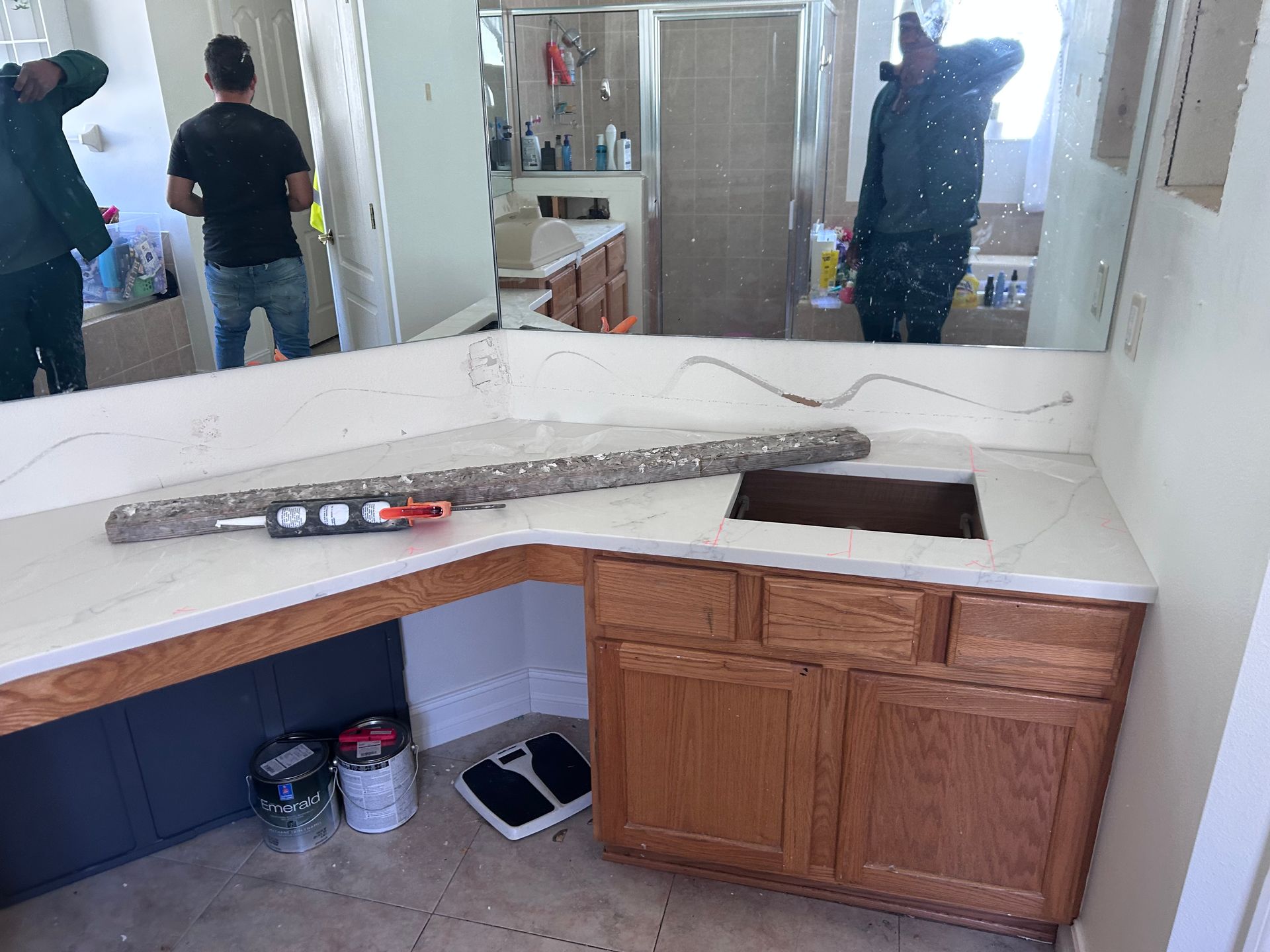 Bathroom remodel: Quartz countertop installation. Workers standing around a vanity with a new sink.