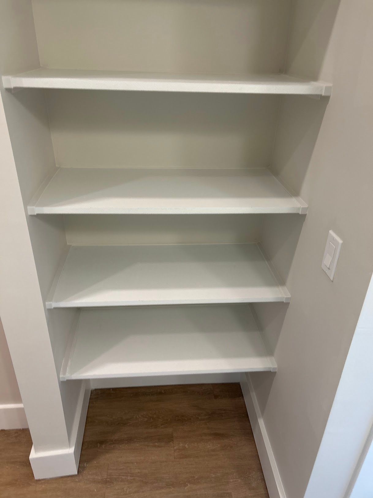 A closet with empty shelves and a wooden floor.