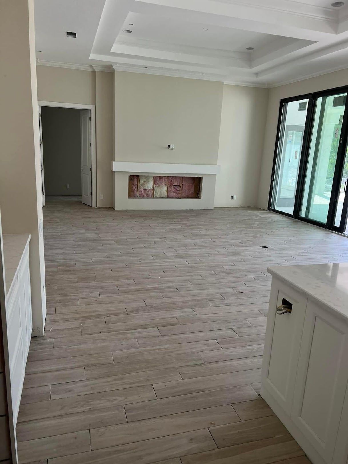 An empty living room with a fireplace and sliding glass doors.