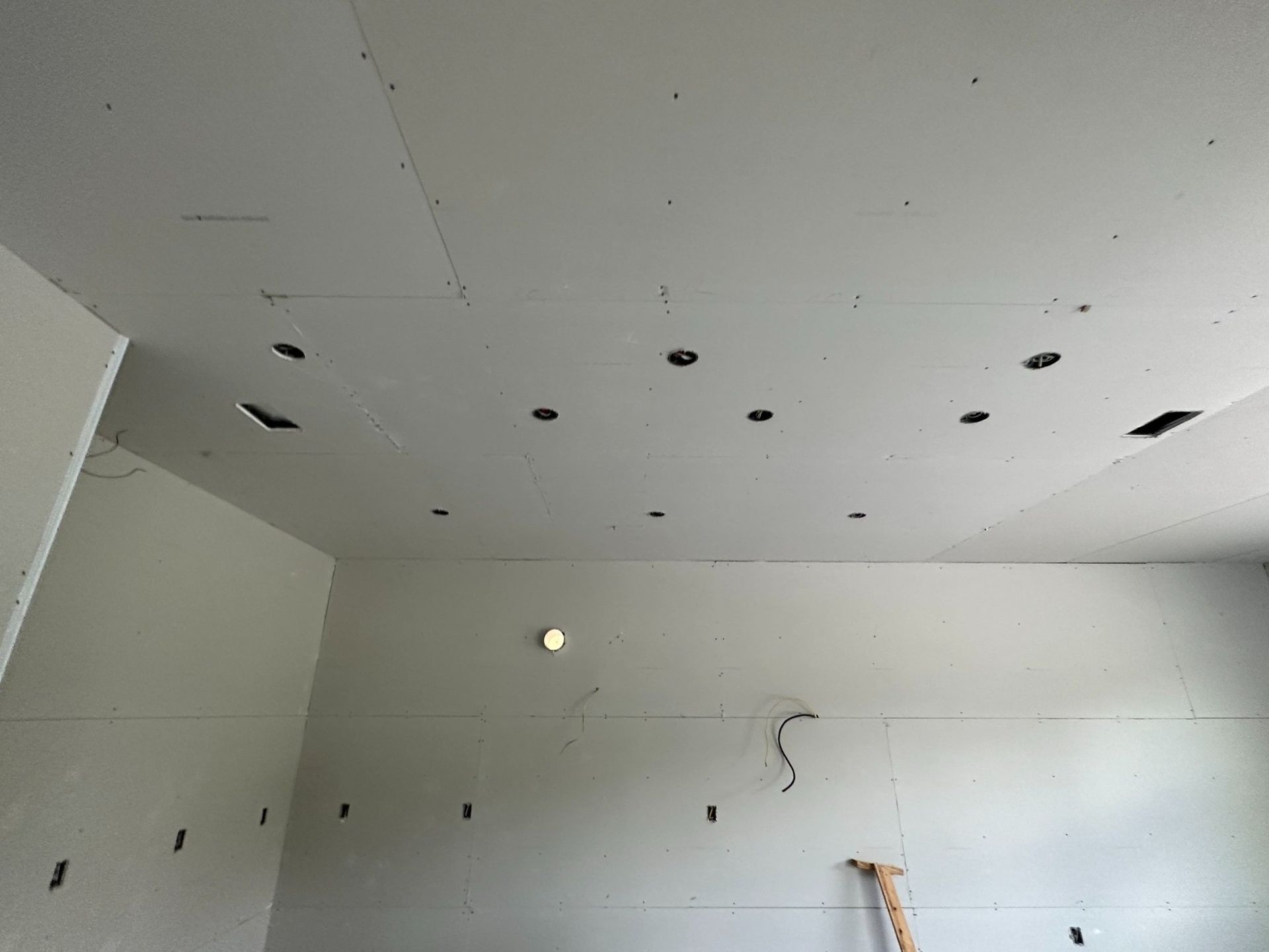 A room with a ceiling that has holes in it and a ladder.