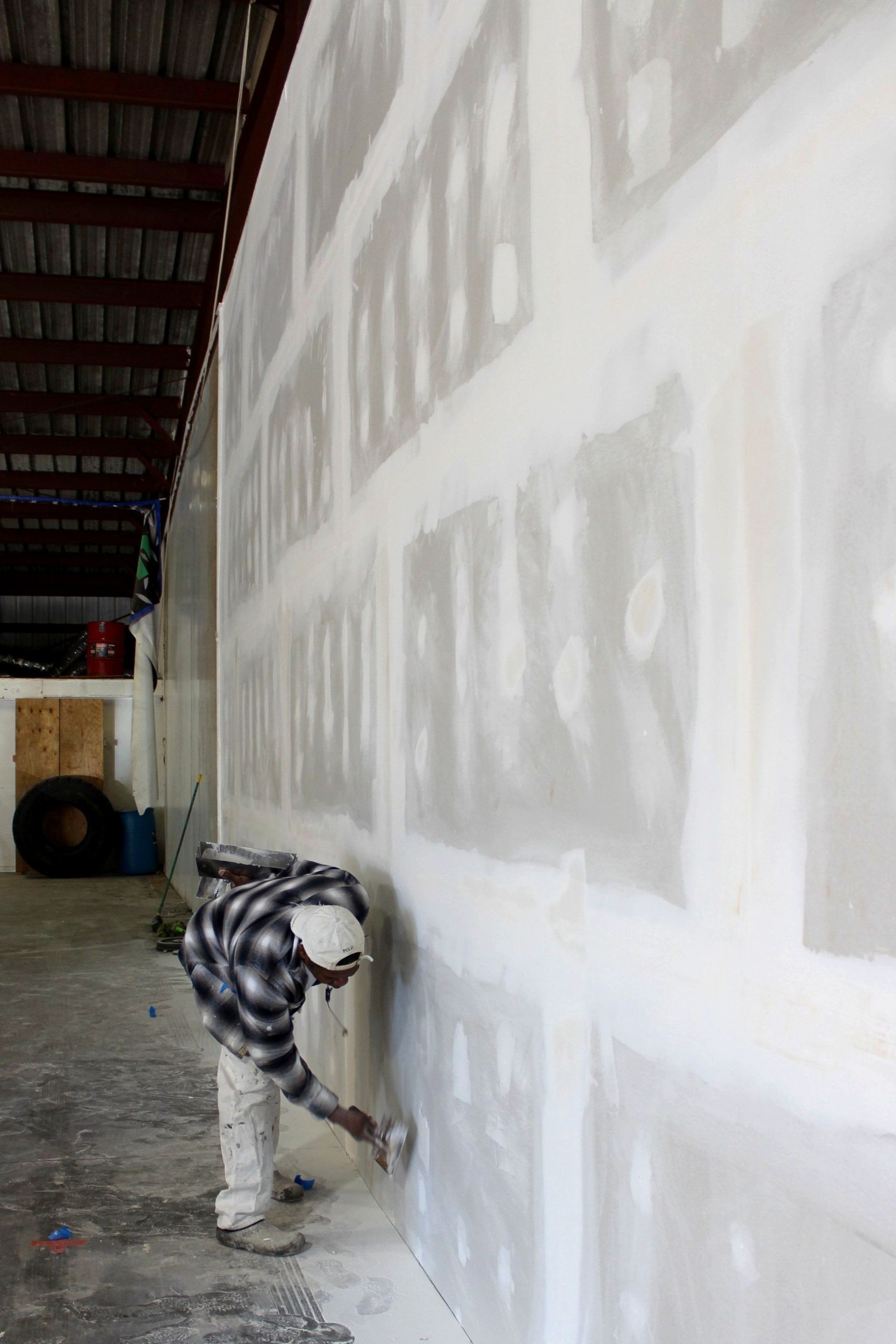 A man is plastering a wall in a building.
