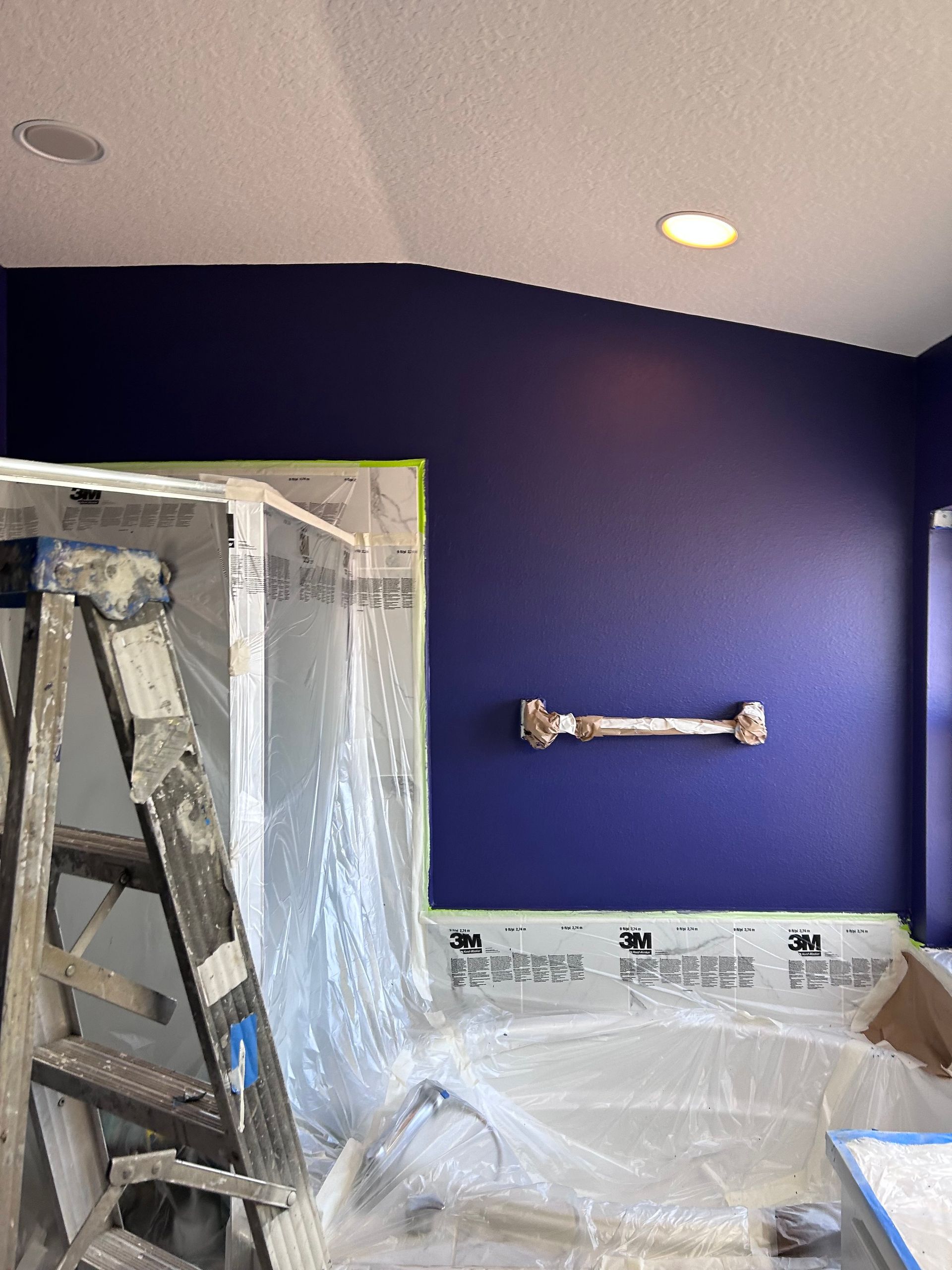 A bathroom is being painted with purple walls and a ladder.