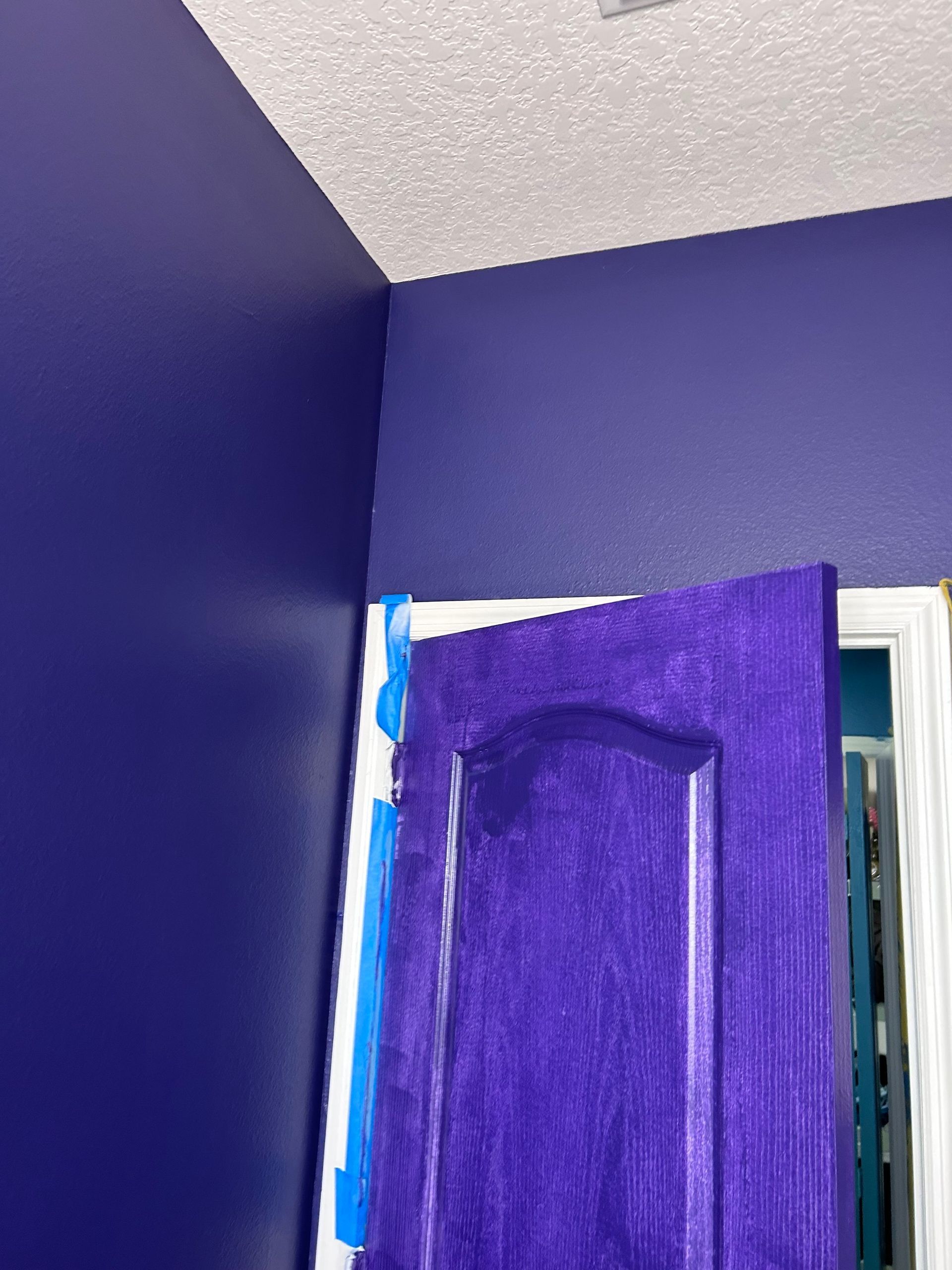 A purple door is painted in a room with purple walls.