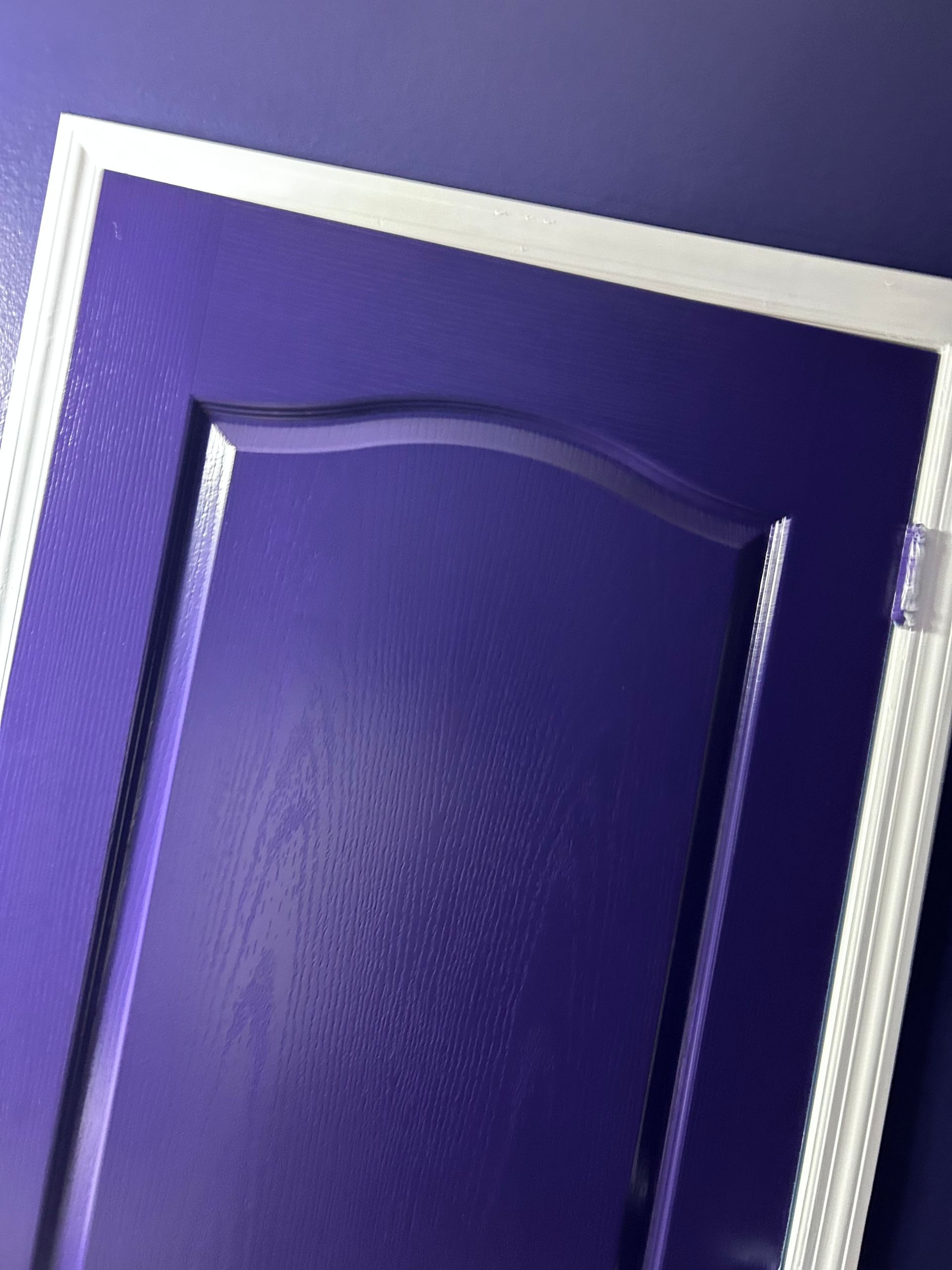 A purple door with a white frame on a purple wall