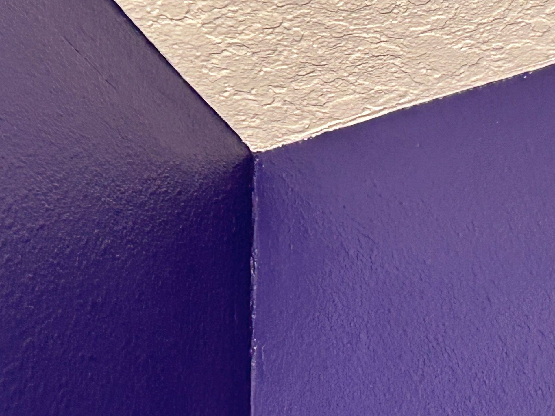 A corner of a purple wall with a white ceiling