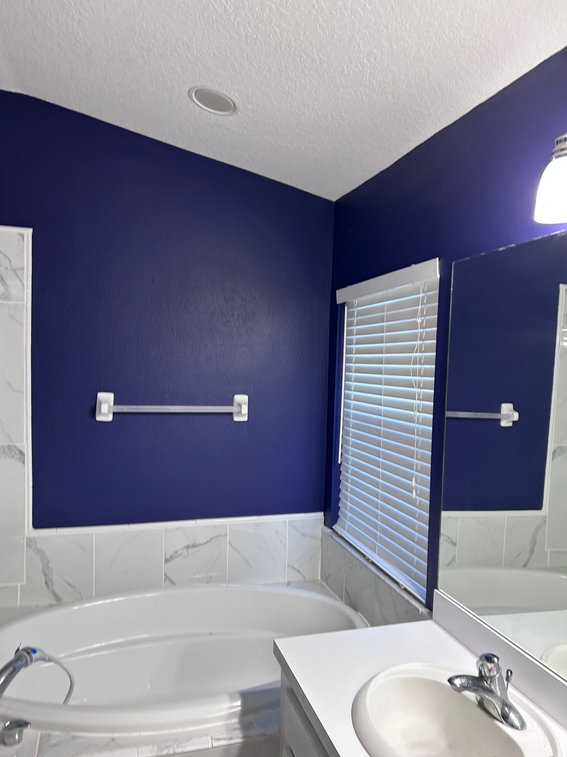 A bathroom with blue walls and a white tub