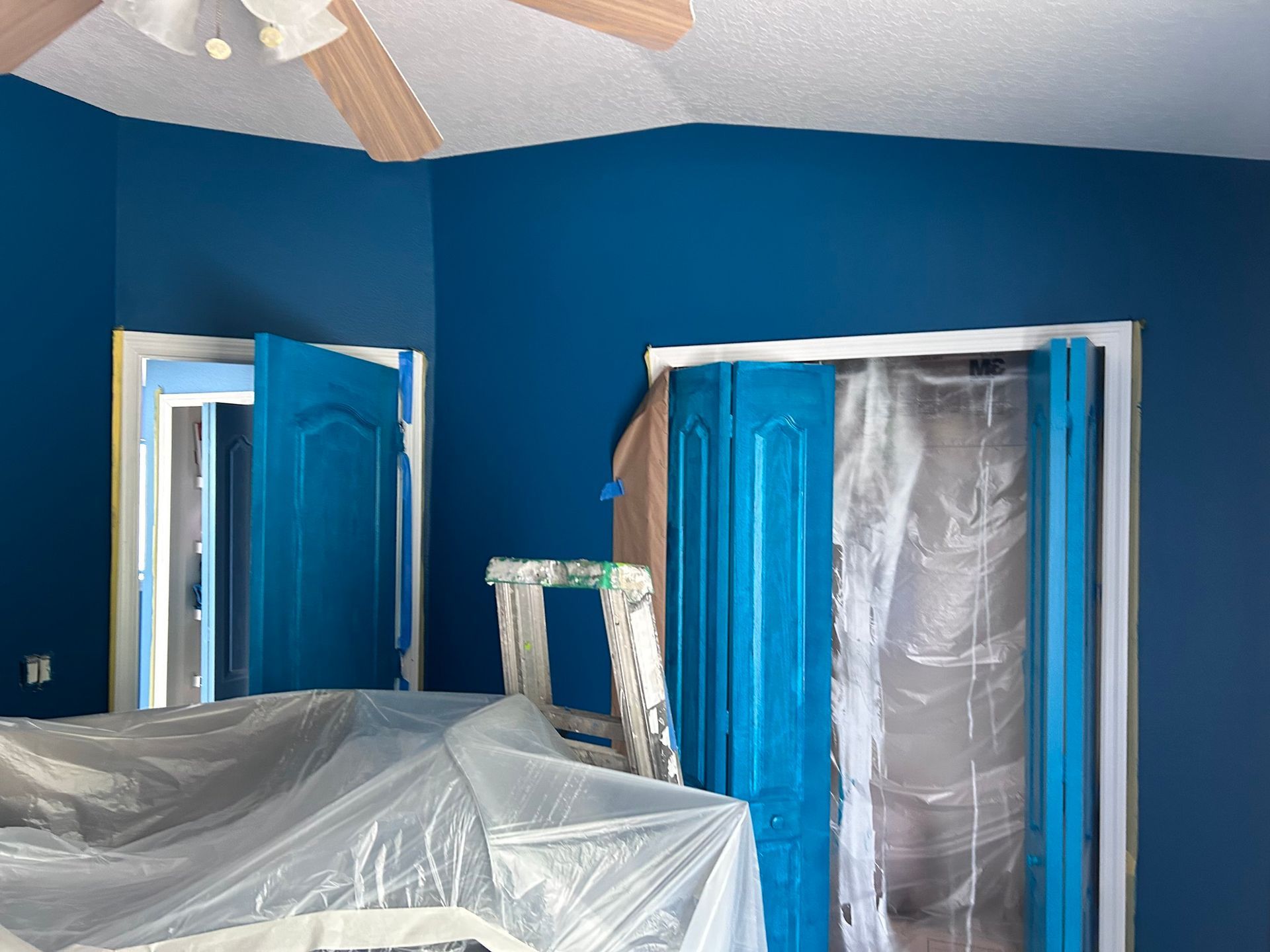 A room with blue walls and blue doors is being painted