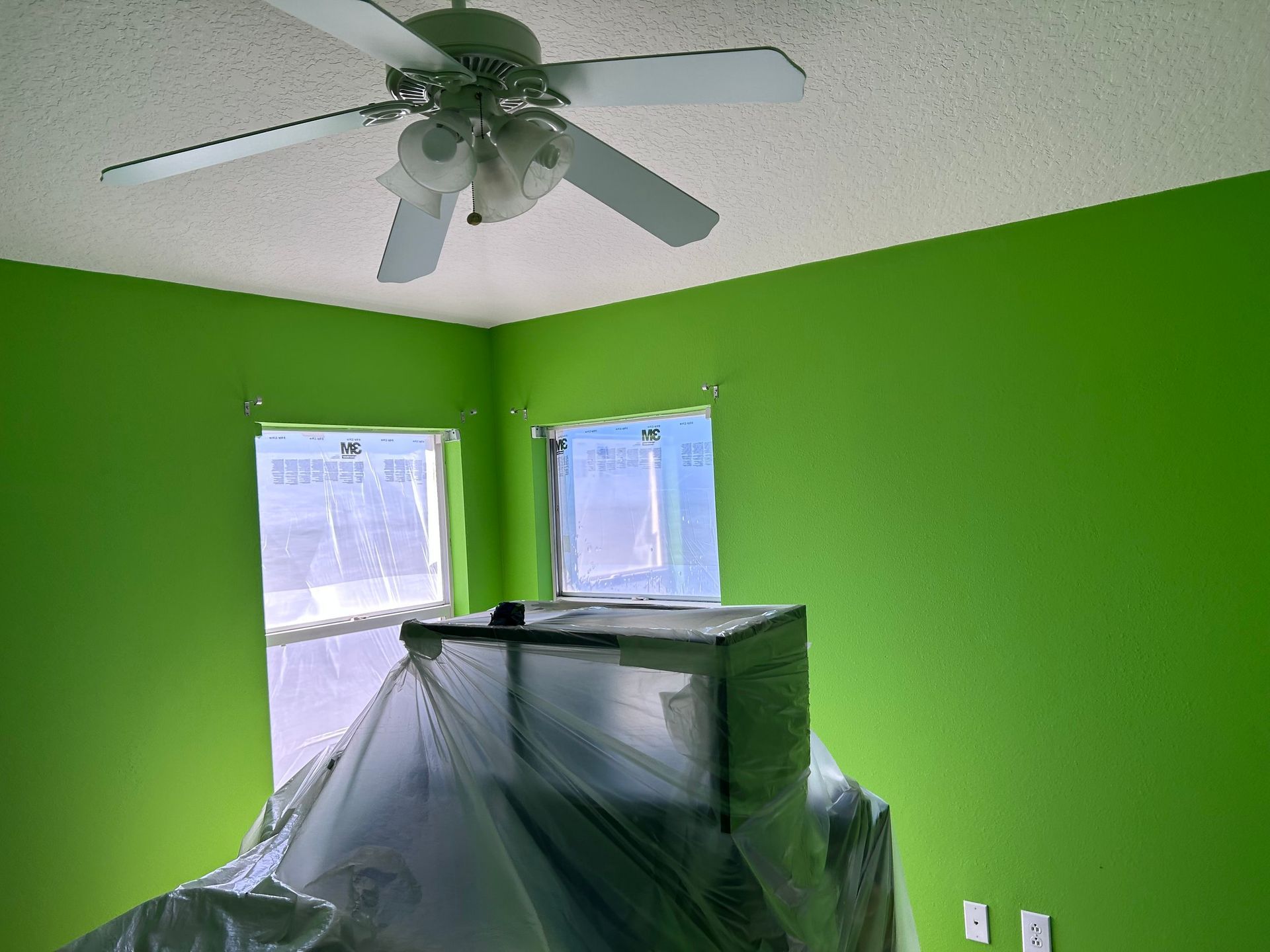 A room with green walls and a ceiling fan