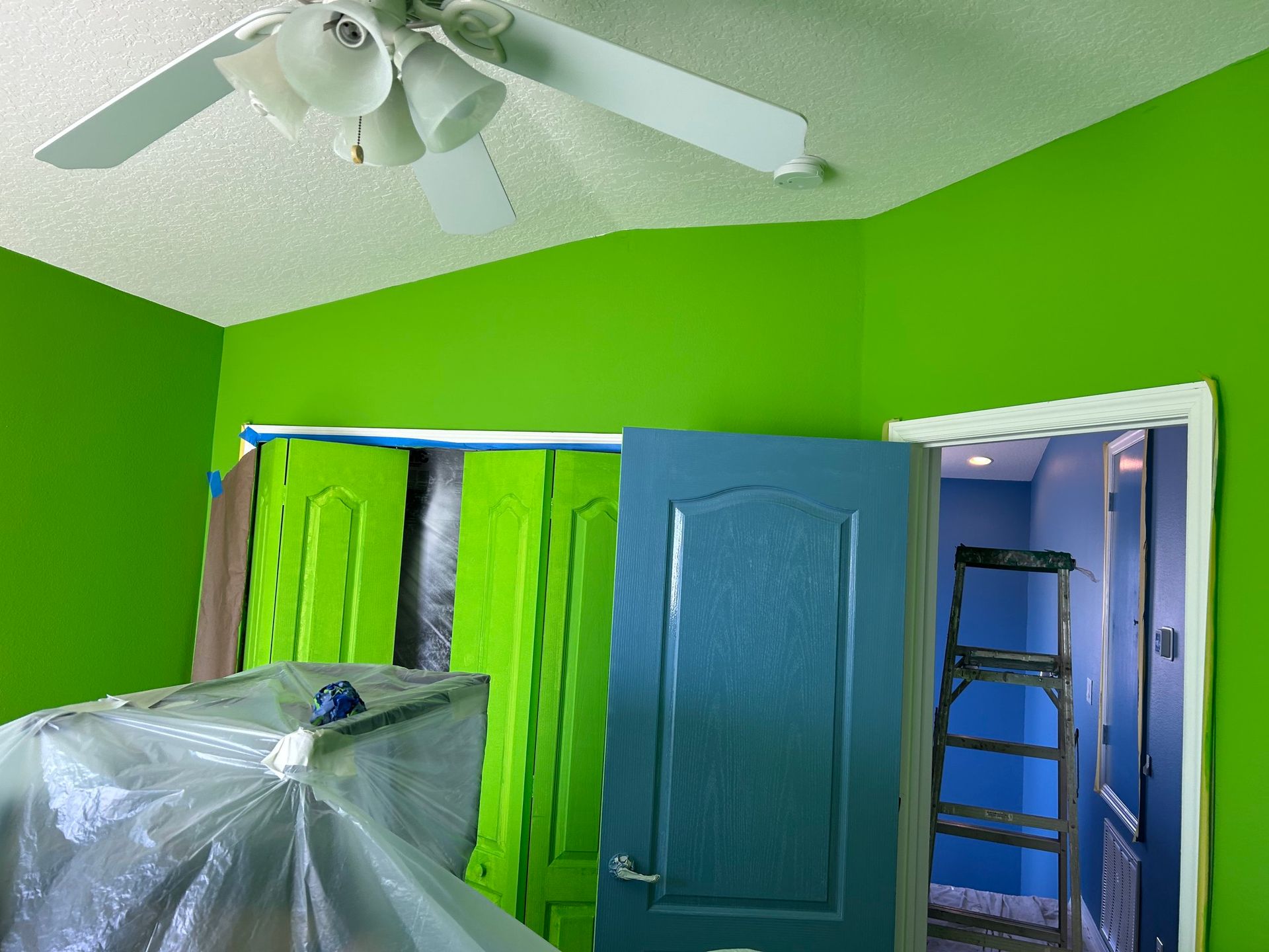 A room with green walls and blue doors and a ceiling fan