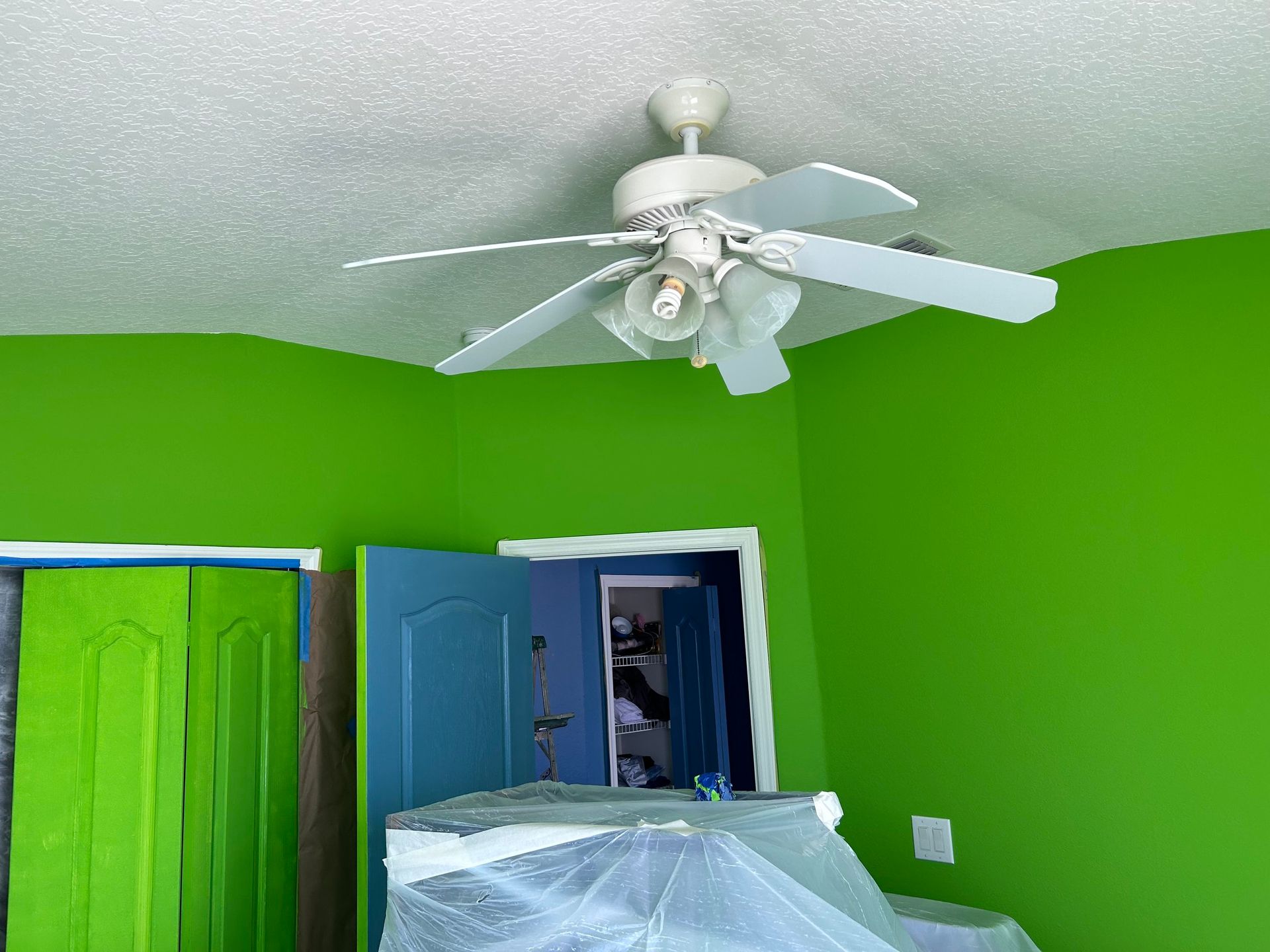 A ceiling fan is hanging from the ceiling in a room with green walls.
