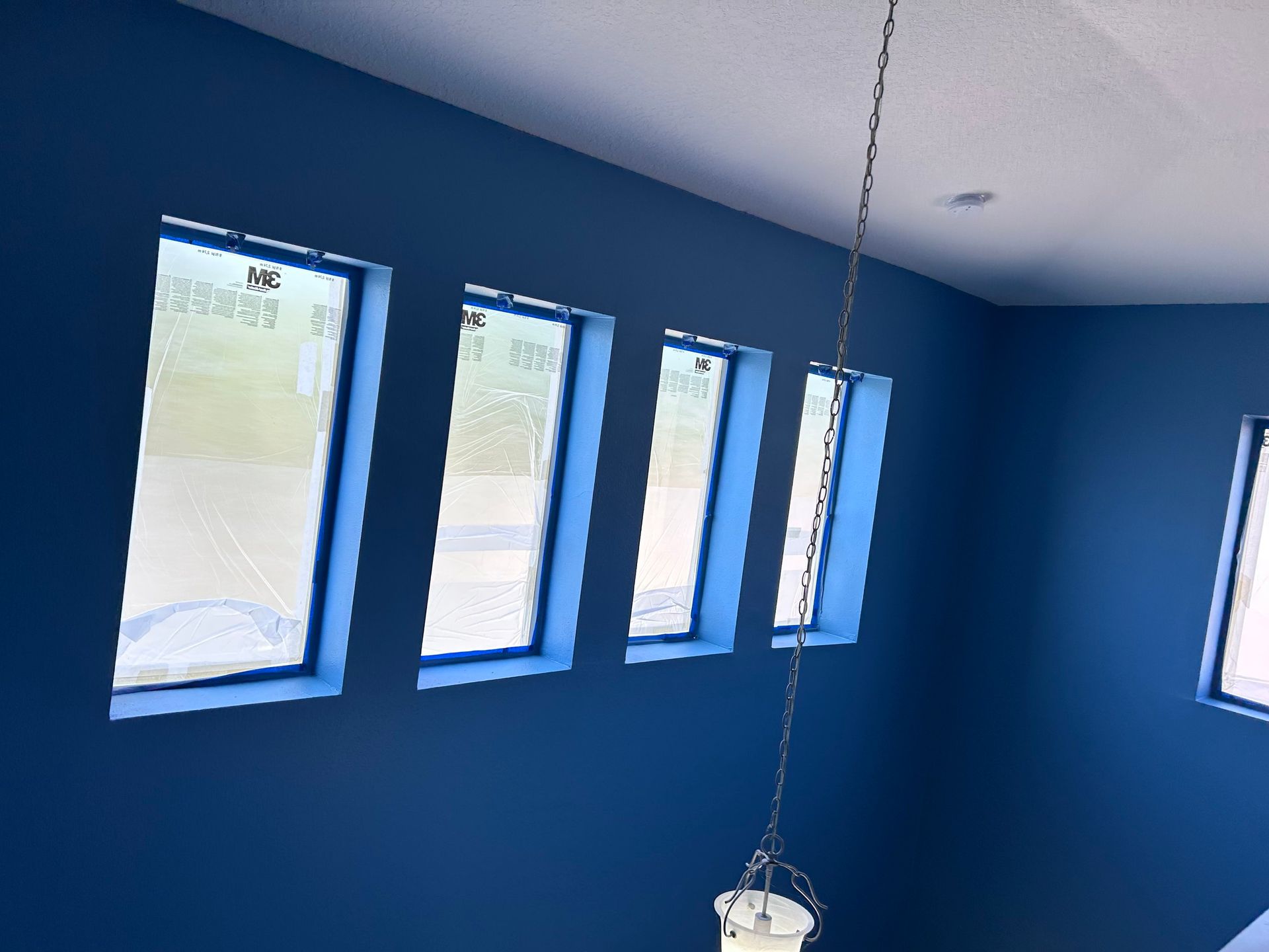 A room with blue walls and a light hanging from the ceiling