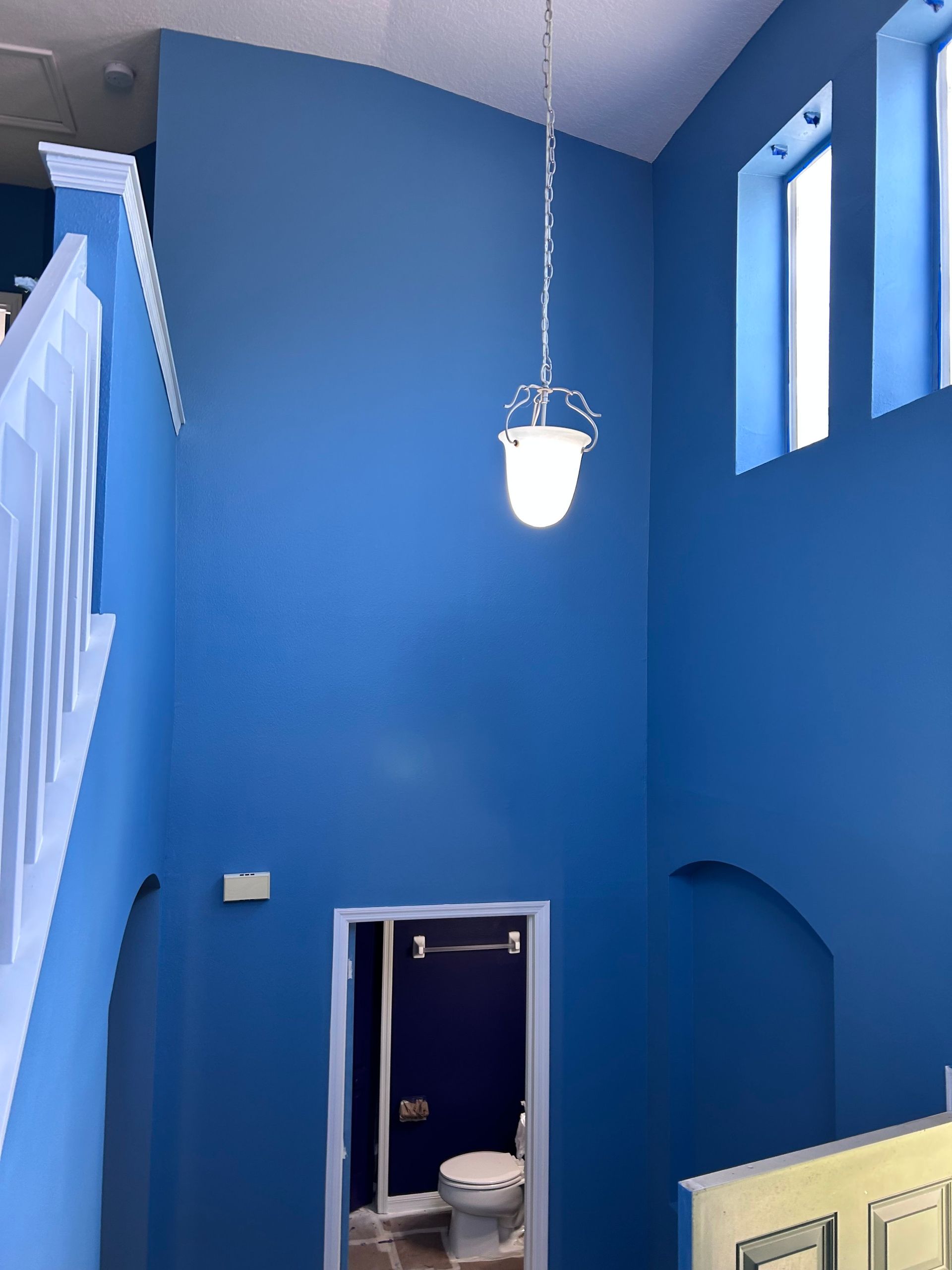 A bathroom with blue walls and a light hanging from the ceiling