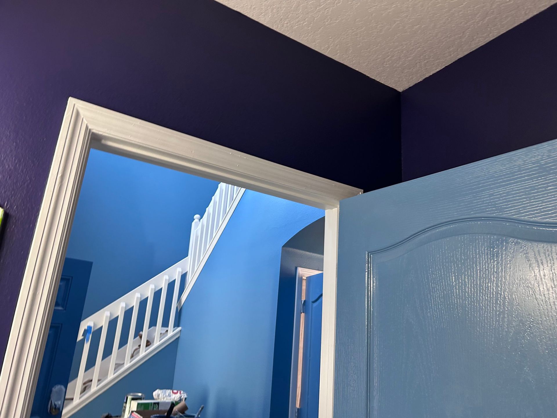 A blue door with purple walls and a white railing