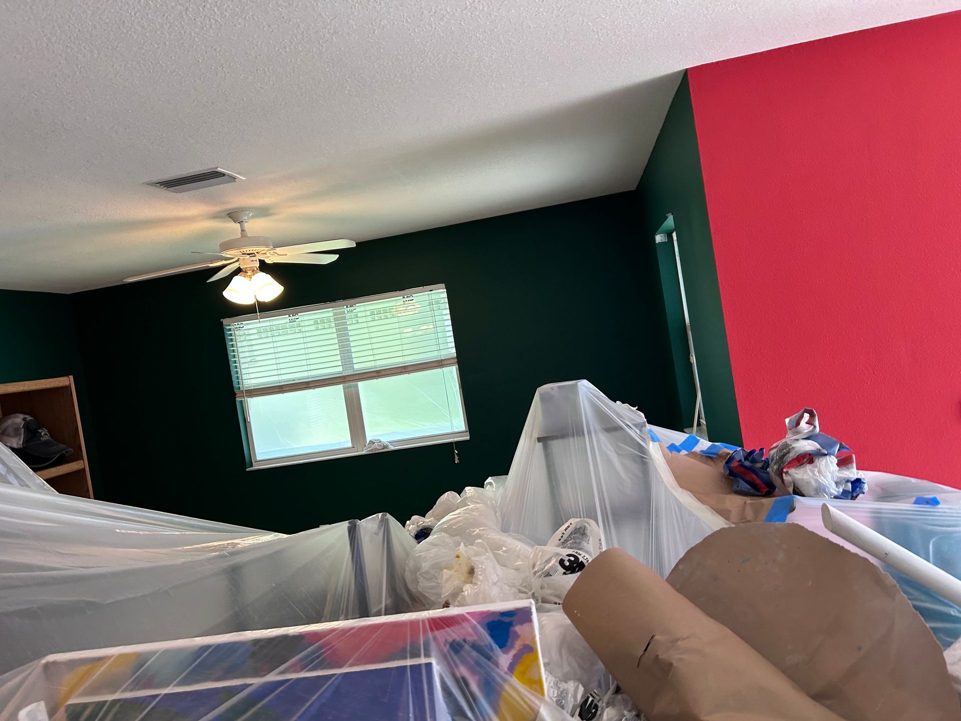 A room with green and red walls and a ceiling fan.