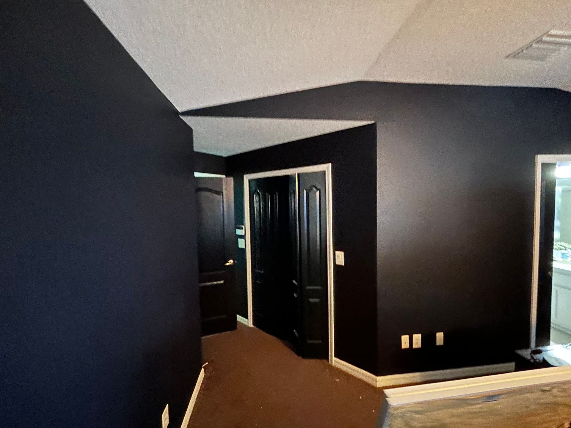 A hallway with black walls and brown carpet