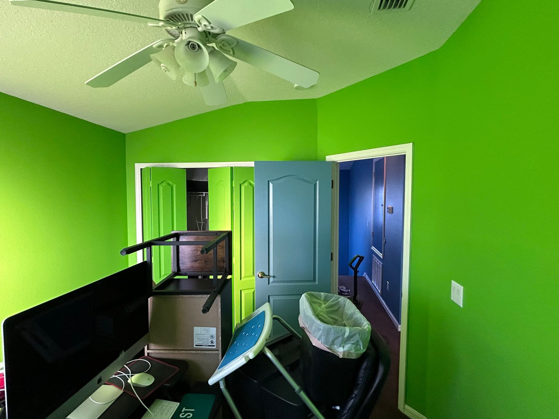 A room with green walls and a ceiling fan.