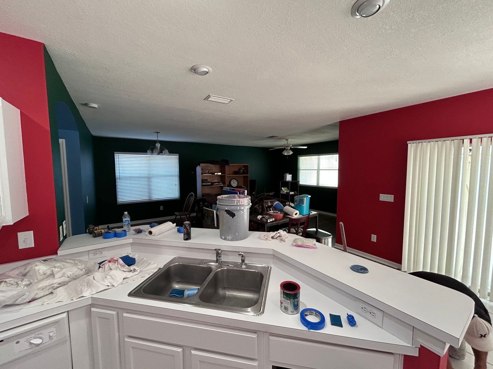 A kitchen with red walls and white cabinets is being painted