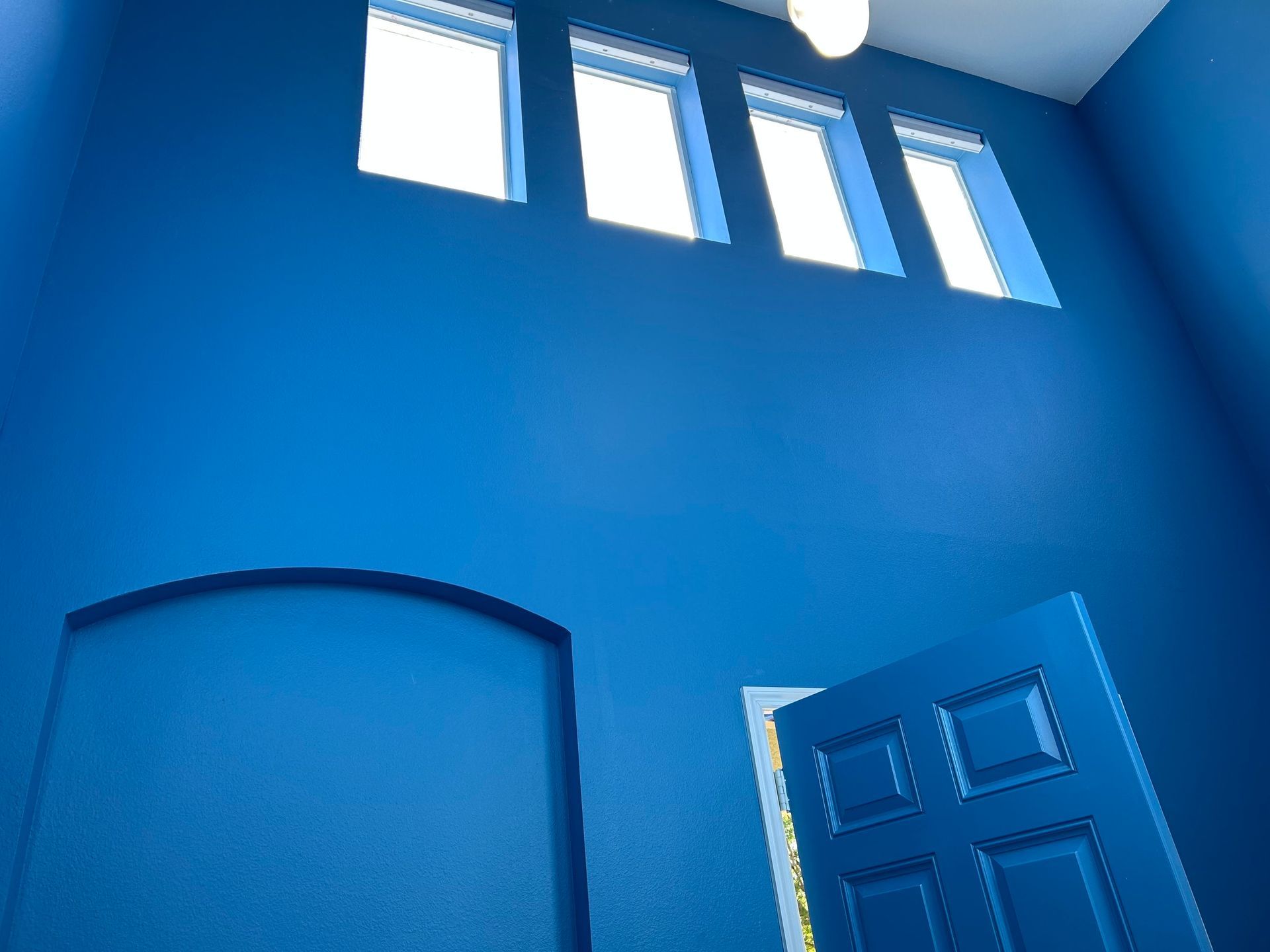 A blue door is open in a room with blue walls
