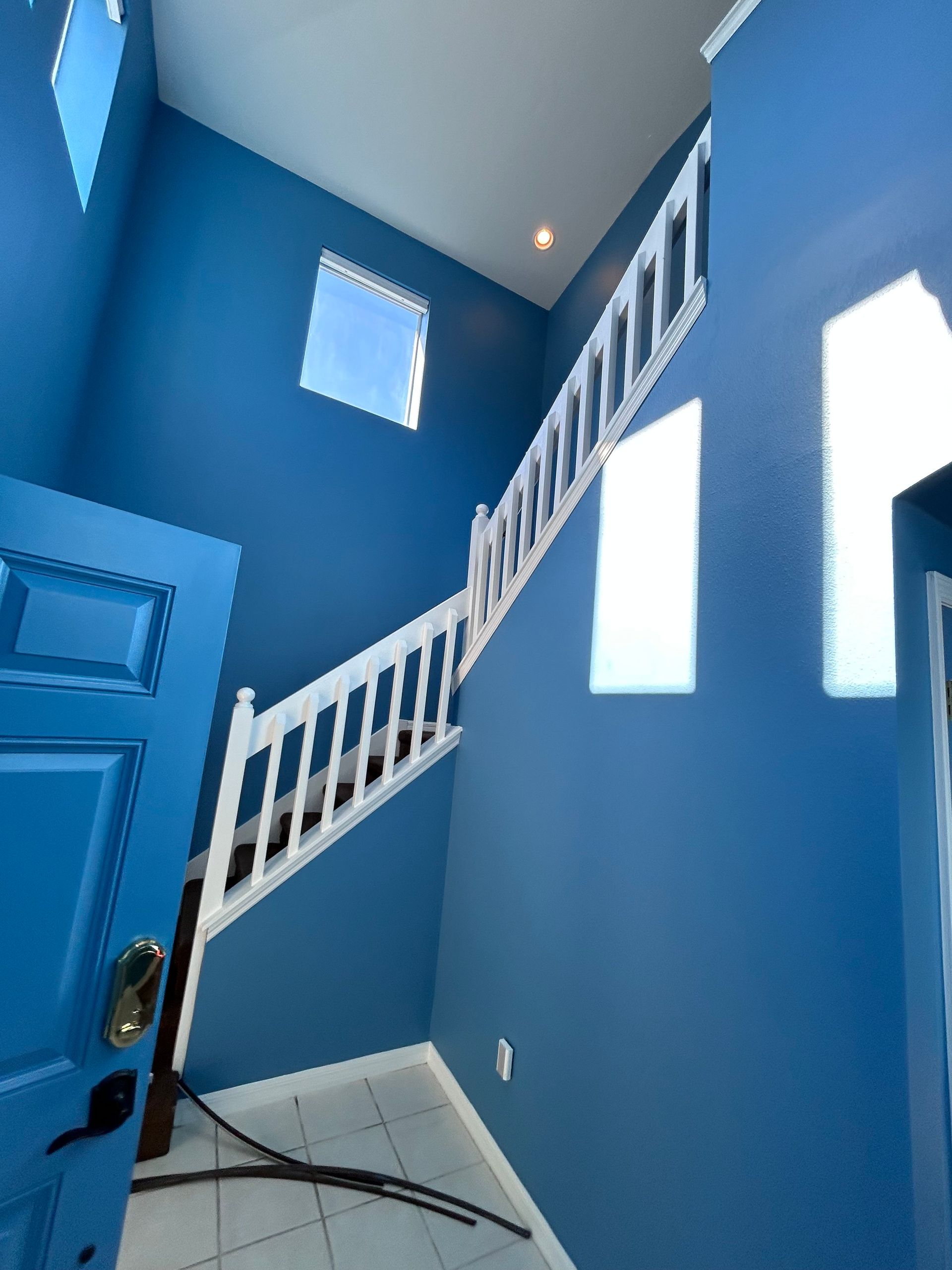 A blue room with stairs and a blue door