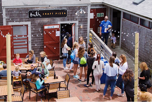 A group of people are standing outside of a restaurant.