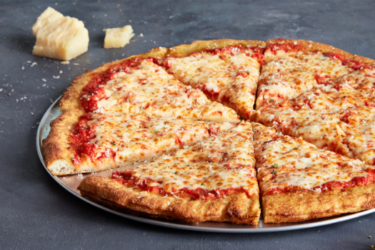 A pizza with tomato sauce and cheese on a metal pan on a table.